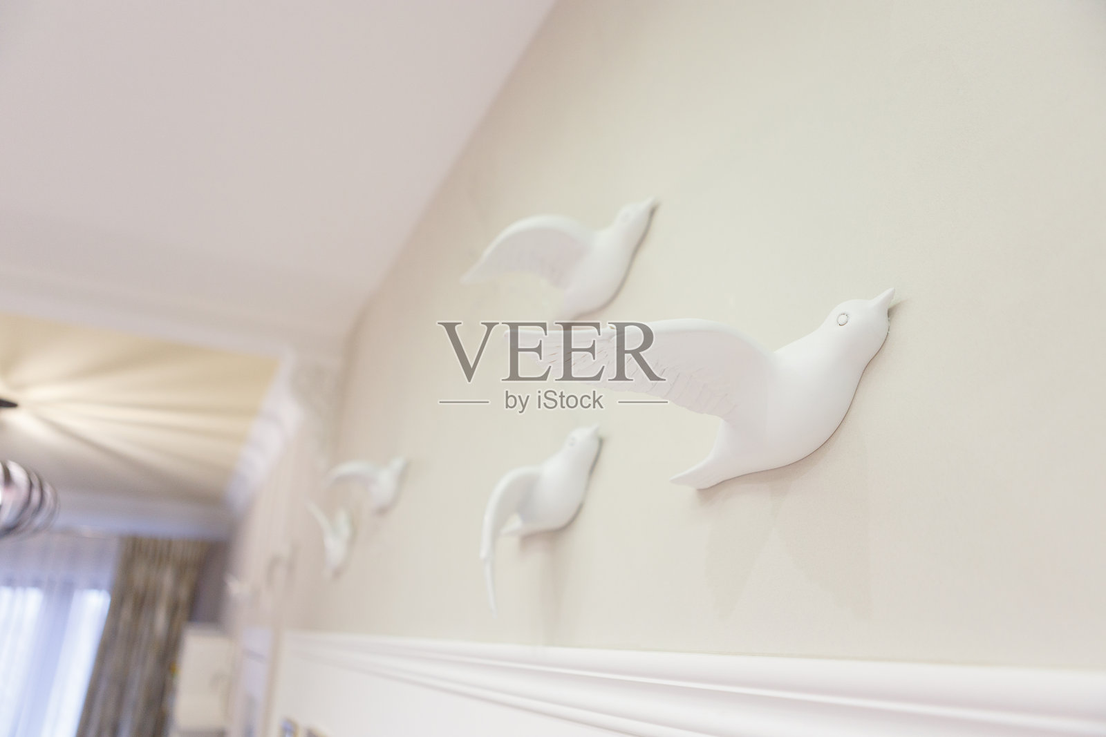 客厅墙上的白色装饰鸟。雕刻成鸟的石膏像。照片摄影图片