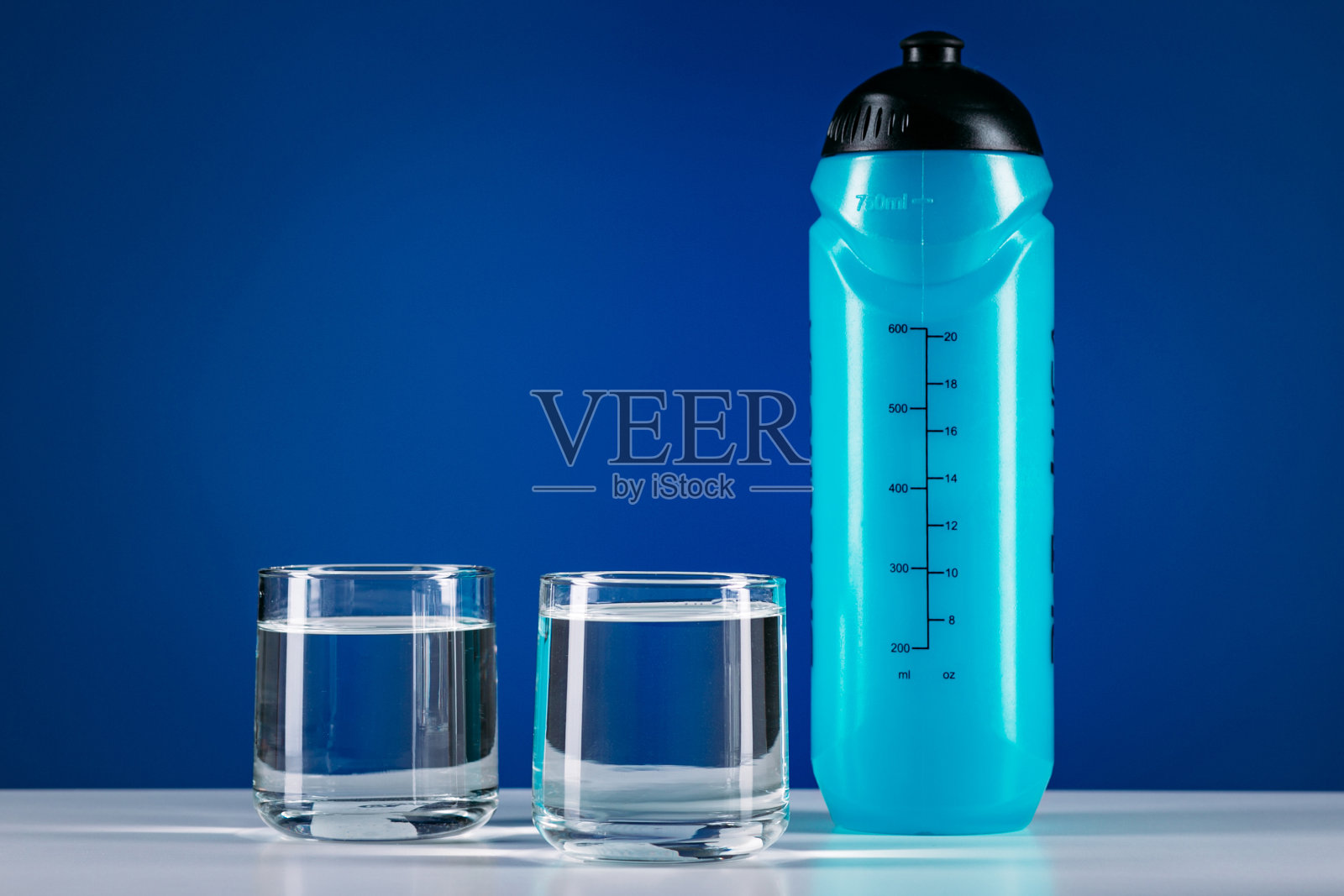 特写蓝色运动水瓶和两杯孤立的蓝色背景照片摄影图片