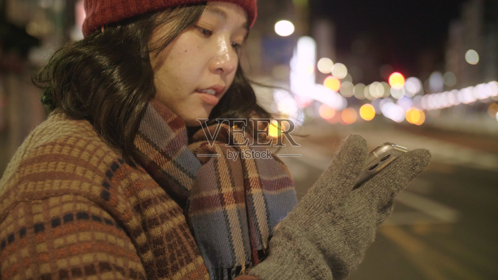 年轻的亚洲妇女戴上羊毛帽子和围巾在东京城市等出租车。照片摄影图片