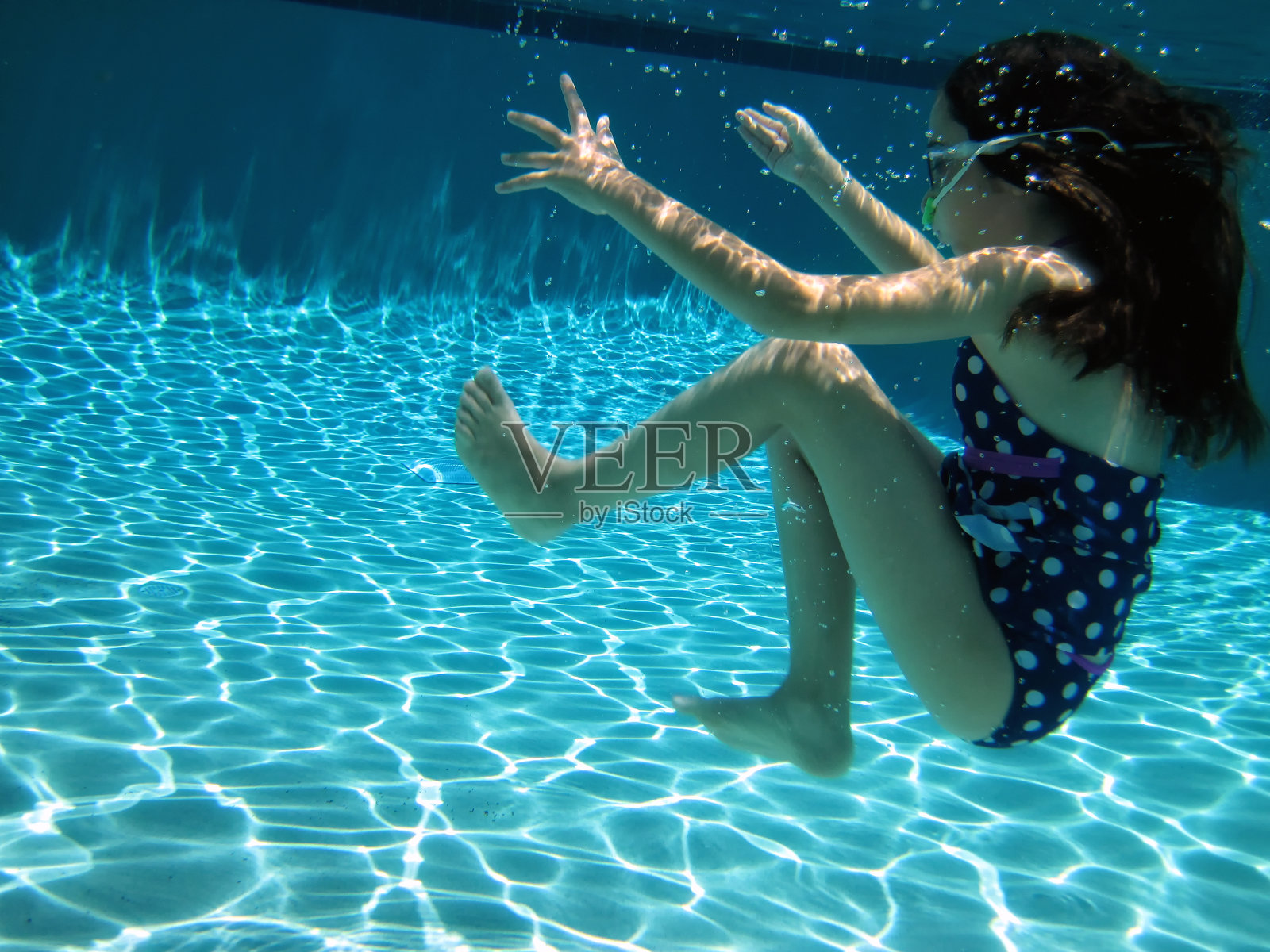 快乐的小女孩在游泳池里游泳照片摄影图片