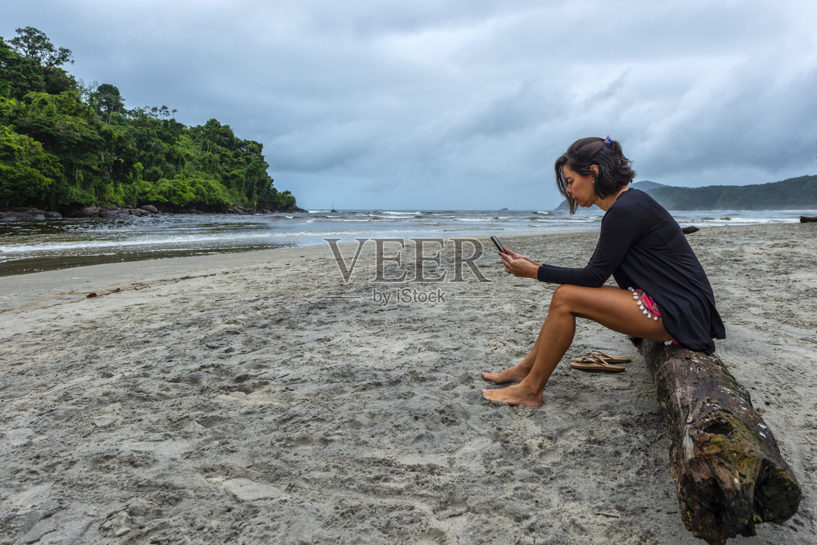 沙滩上的女人用科技对抗现实生活照片摄影图片