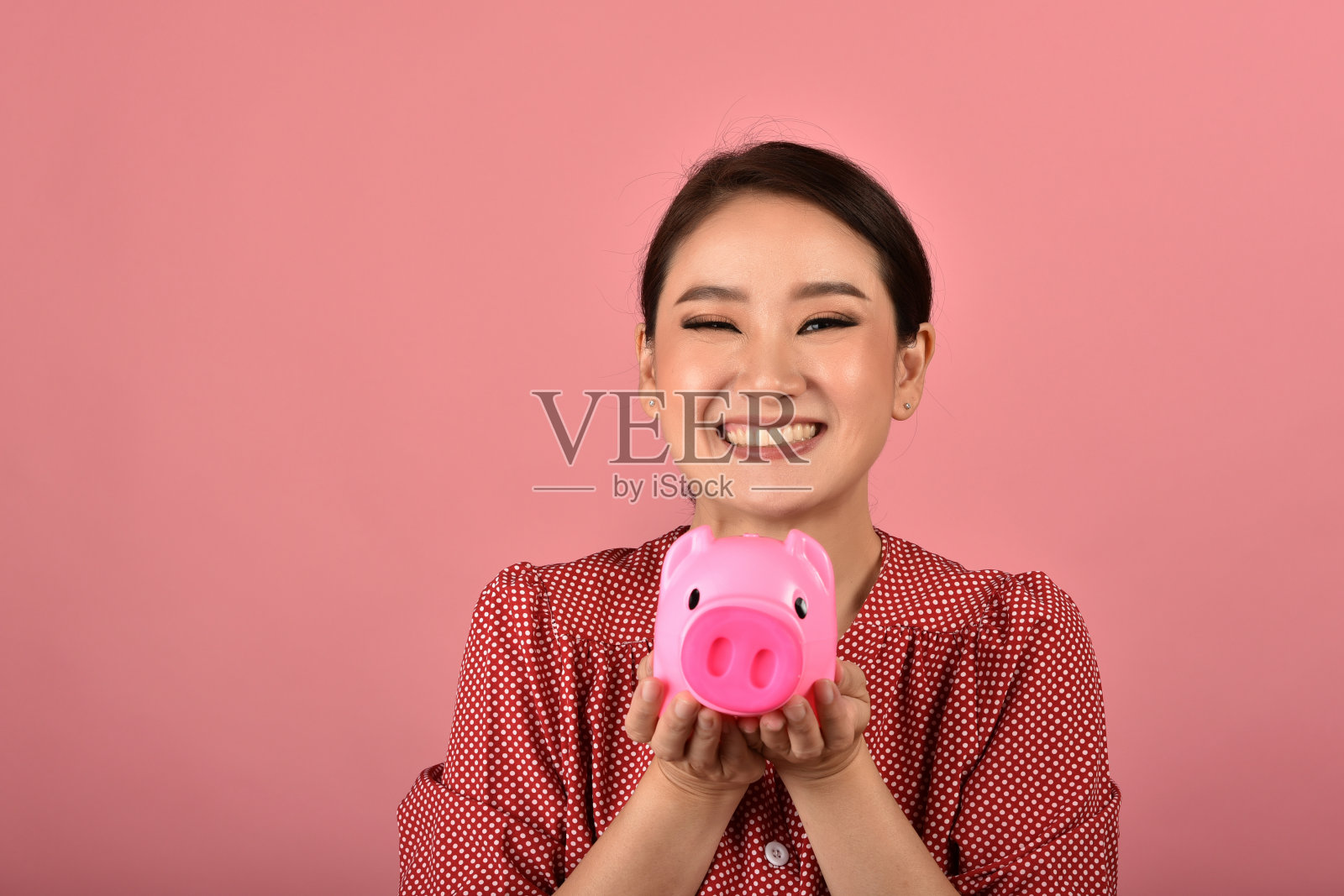 存钱，亚洲女人微笑着拿着粉红色的存钱罐，财富和投资理财保险。照片摄影图片