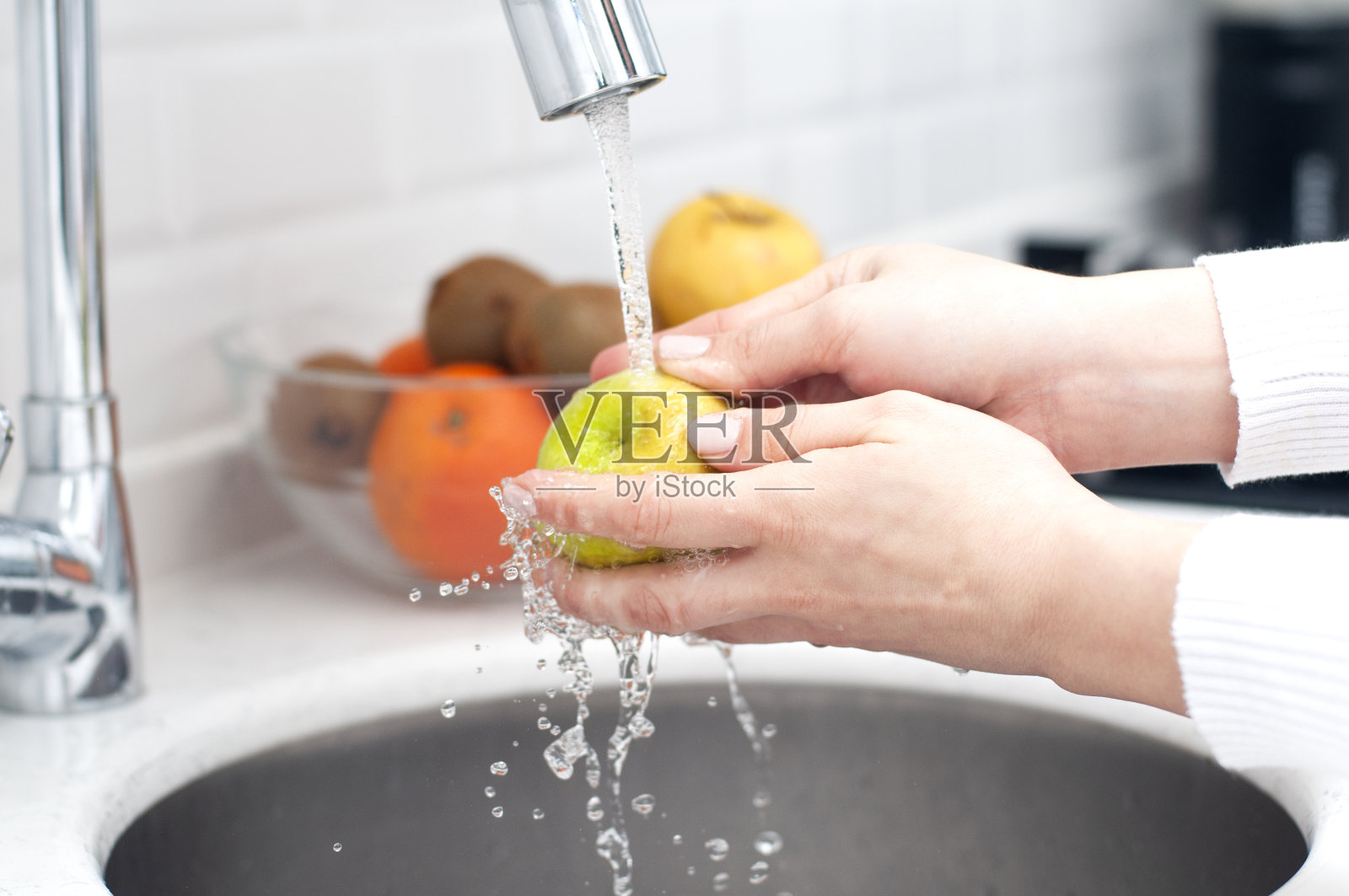 靠近女性的手在厨房水槽下洗苹果。年轻的家庭主妇准备健康膳食。照片摄影图片