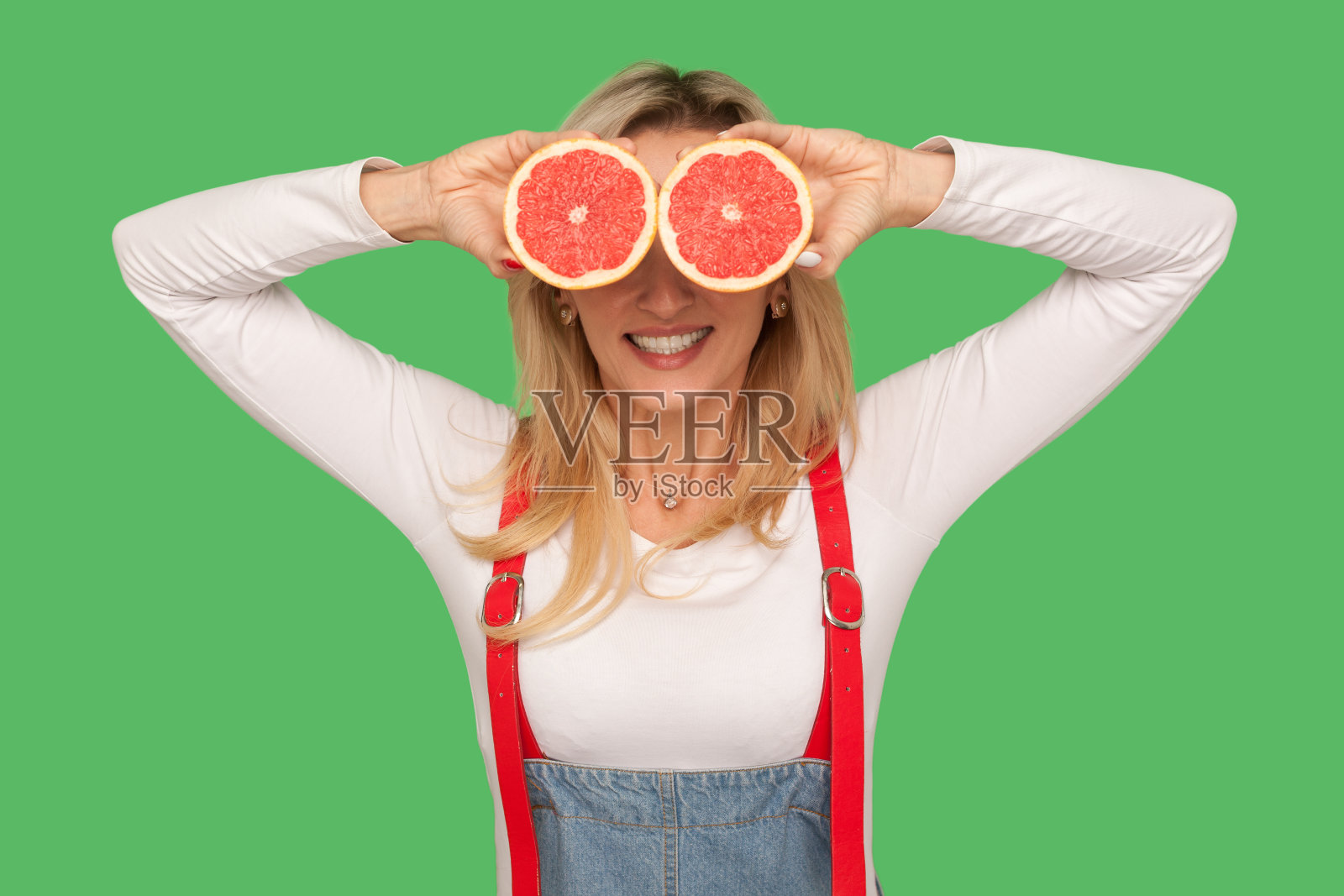 新鲜水果，天然有机食品。快乐时尚的女人用切好的葡萄柚遮住眼睛的肖像照片摄影图片