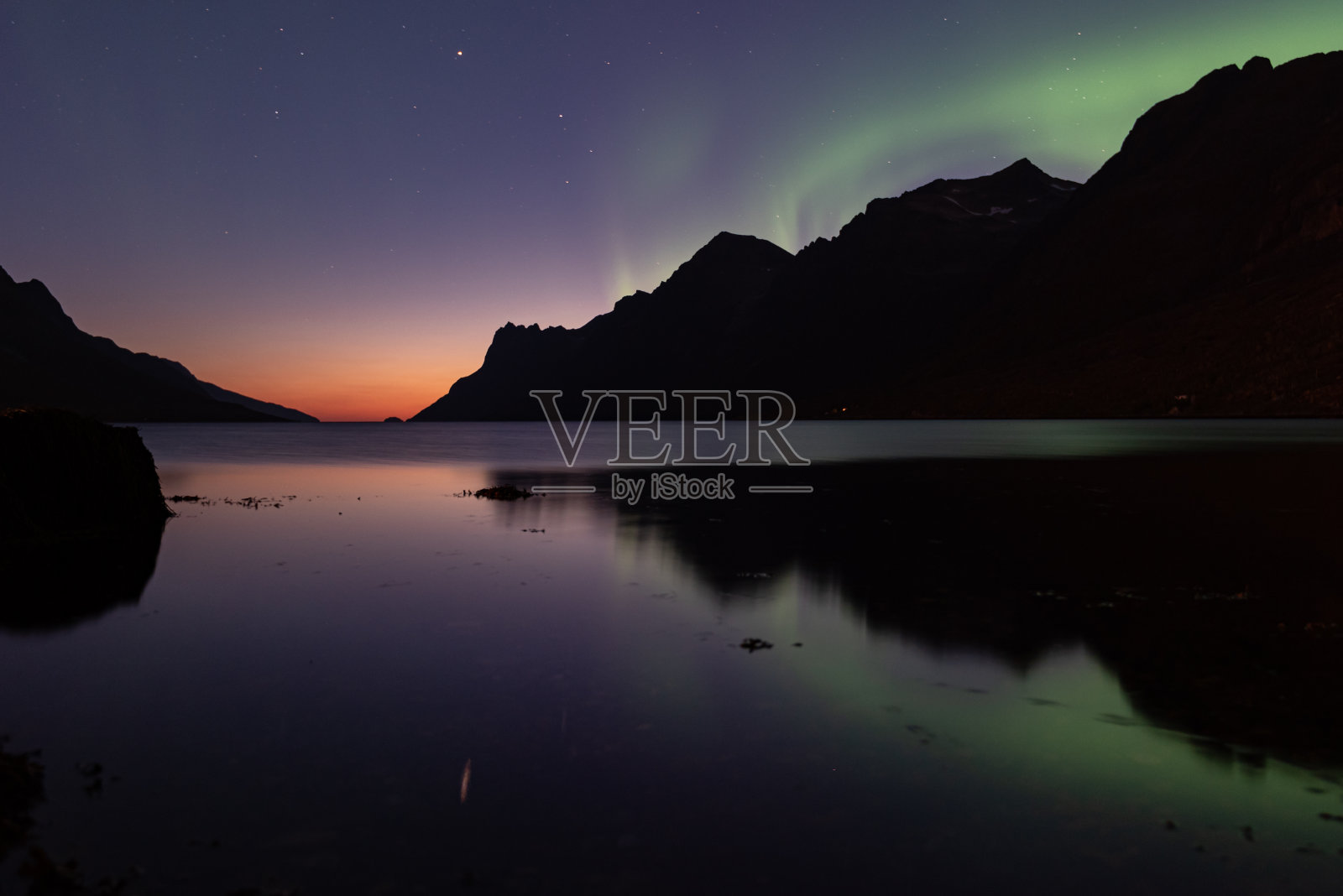 北极光背景下的北极日落，挪威北部照片摄影图片