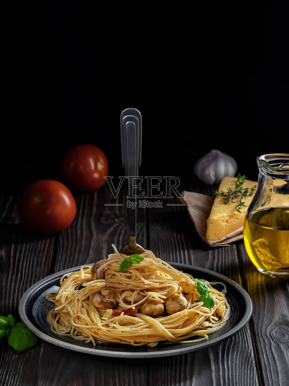 带有奶酪、蘑菇和蔬菜的通心粉，位于深色木质背景上。把意大利面插在盘子里的叉子。特写，浅景深。素食午餐的概念。照片摄影图片