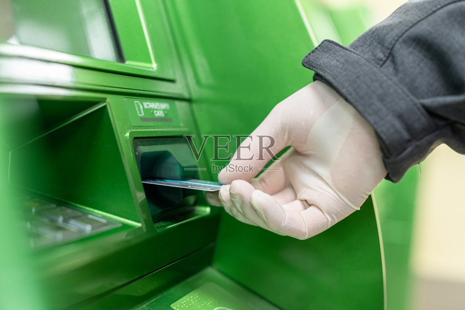 男人们戴上防护橡胶手套，将信用卡放在ATM机上以防冠状病毒。大流行。照片摄影图片