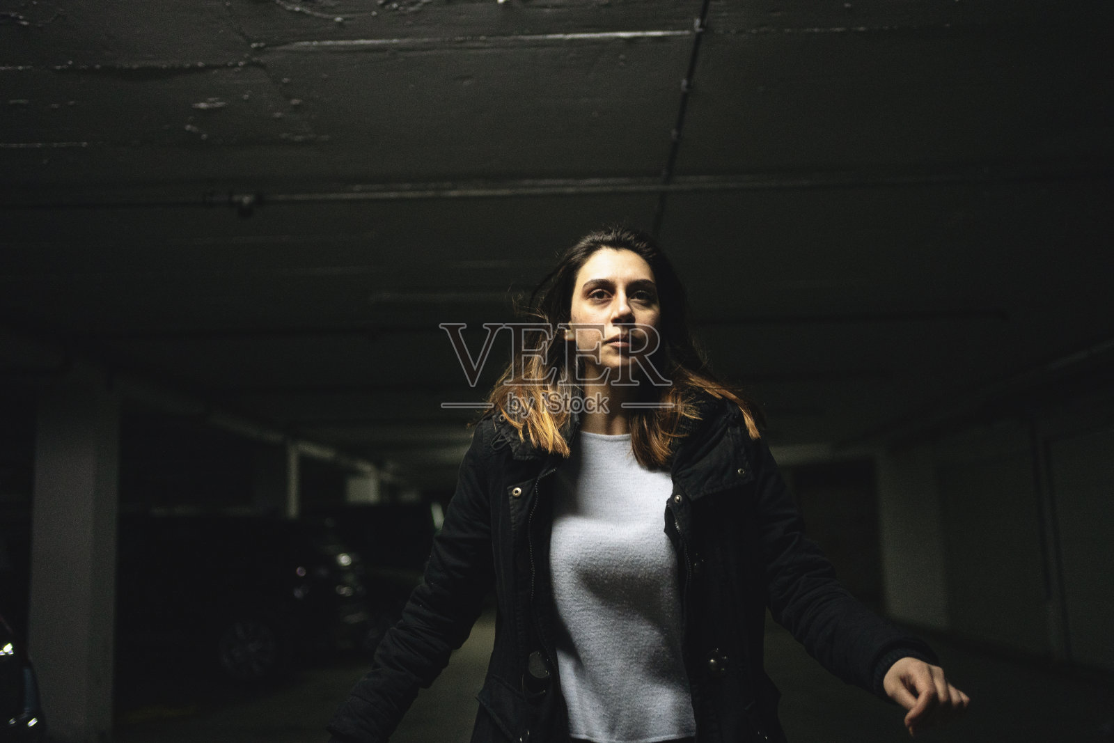 年轻女子惊恐地在地下车库奔跑。照片摄影图片