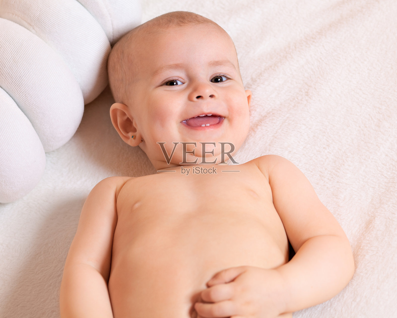 婴儿仰面躺着，望着画框，开心地笑着。照片摄影图片