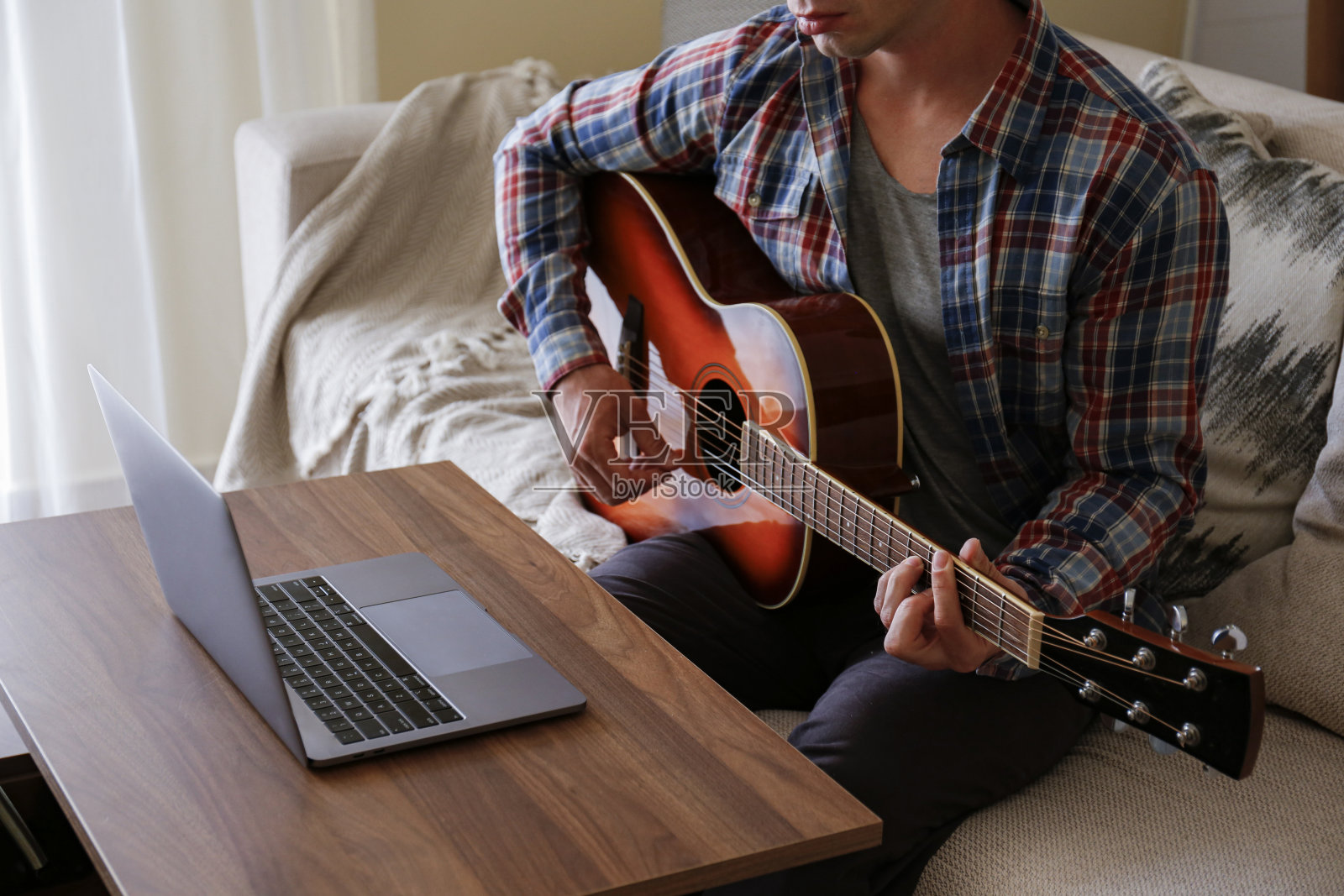 在线音乐学院的概念。男人在家里学习放原声吉他。照片摄影图片