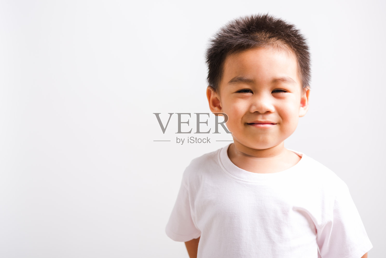 特写脸亚洲泰国肖像快乐可爱的小男孩微笑着穿t恤他看相机，工作室拍摄，孤立在白色的背景与复制空间照片摄影图片