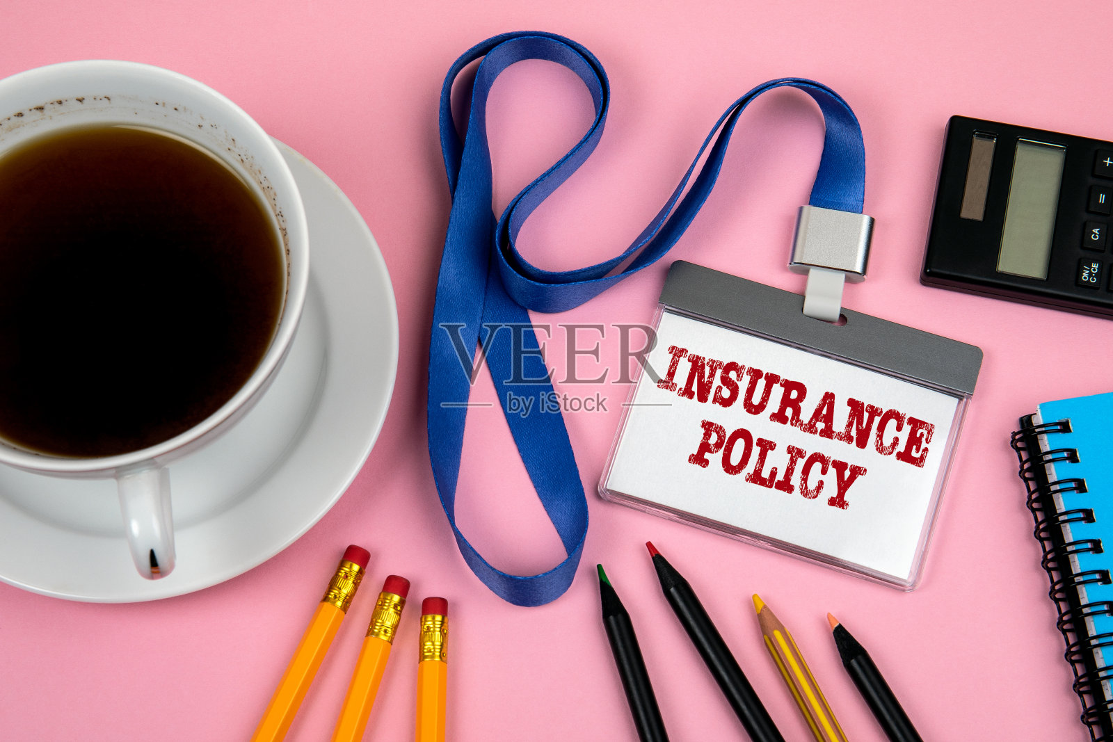 保险政策。员工身份，黑色计算器和一杯粉红色背景的咖啡照片摄影图片