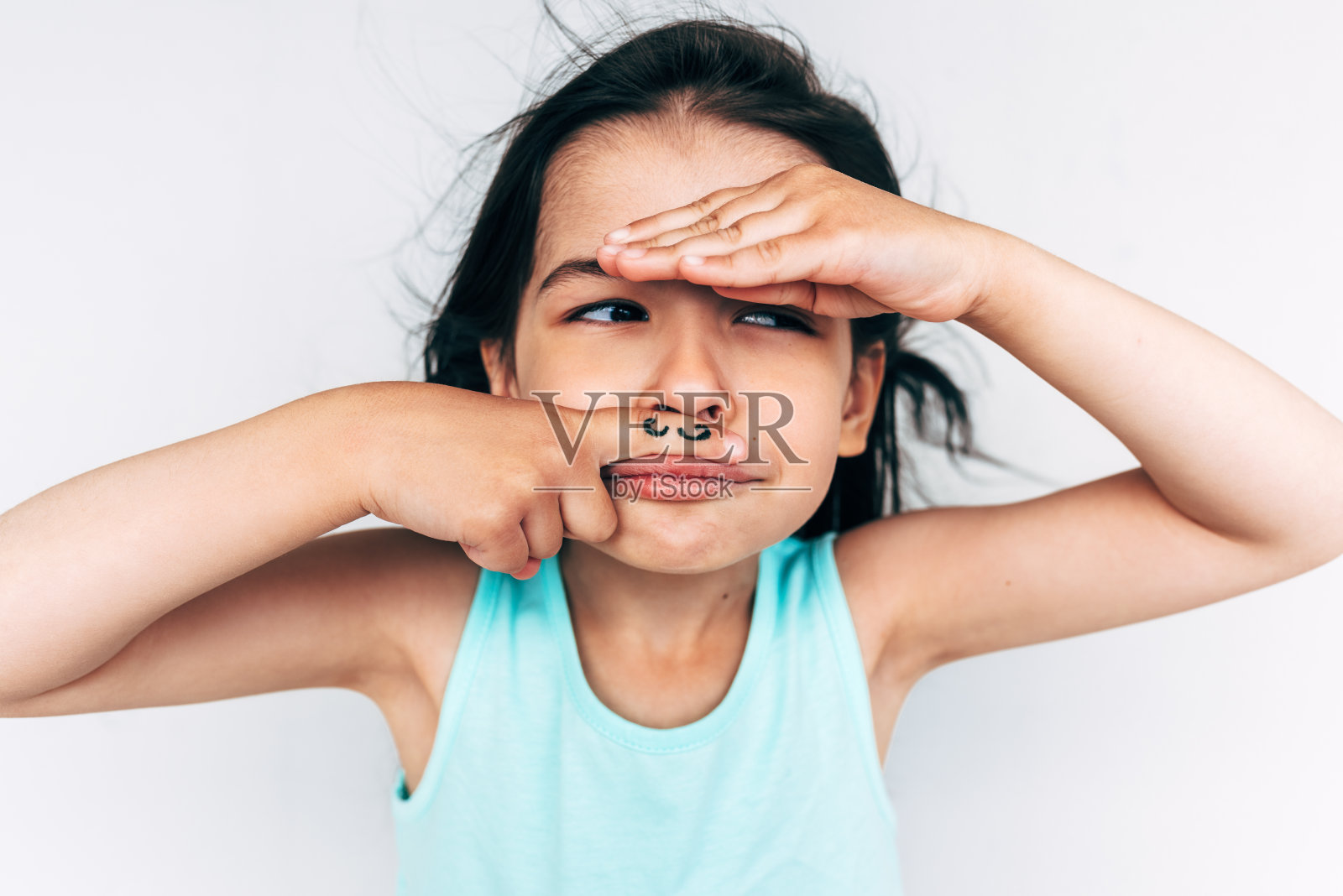 调皮的小女孩的肖像做鬼脸与胡子画在她的食指把它在鼻子下面。有趣的孩子在白色的墙上玩得很开心。人的表情，孩子的概念照片摄影图片