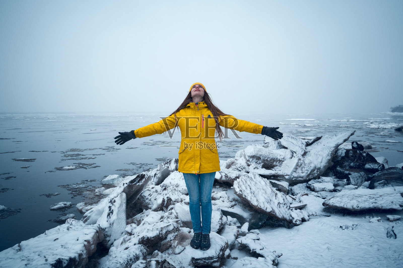 穿着黄色夹克的年轻女子站在冰上照片摄影图片