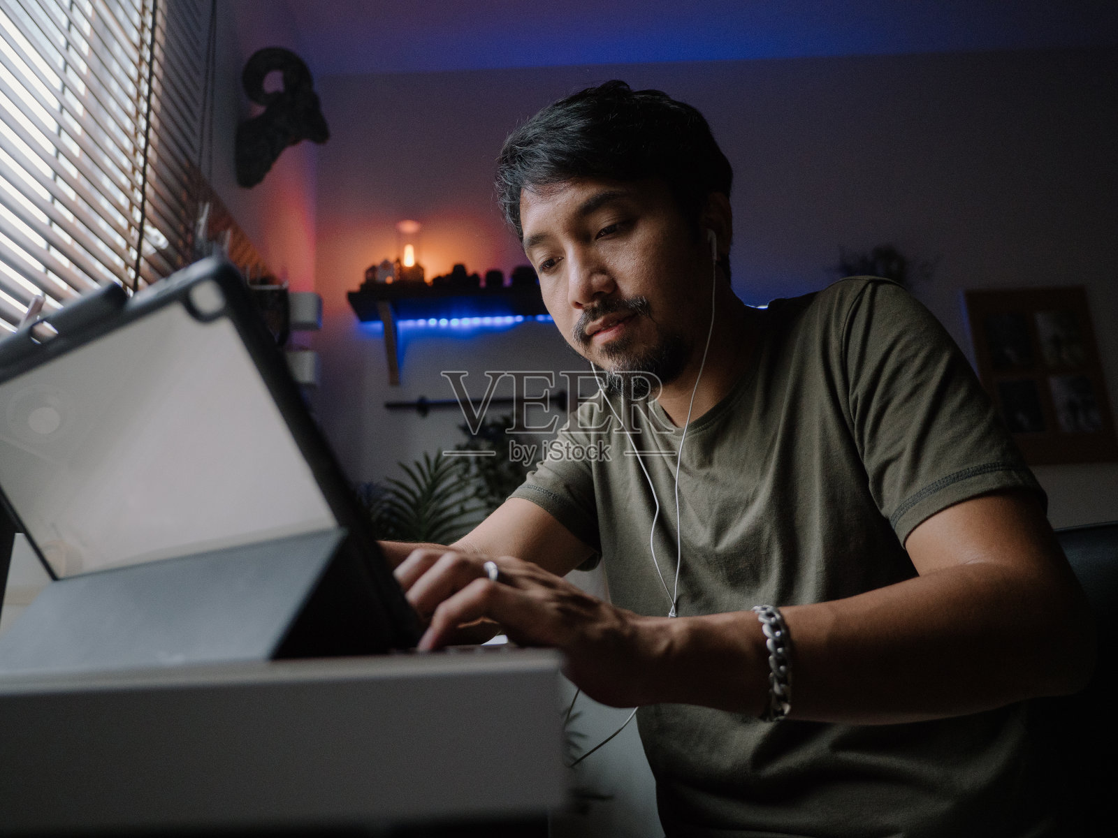 成熟的亚洲男人在现代家庭办公室工作的数字平板电脑。照片摄影图片