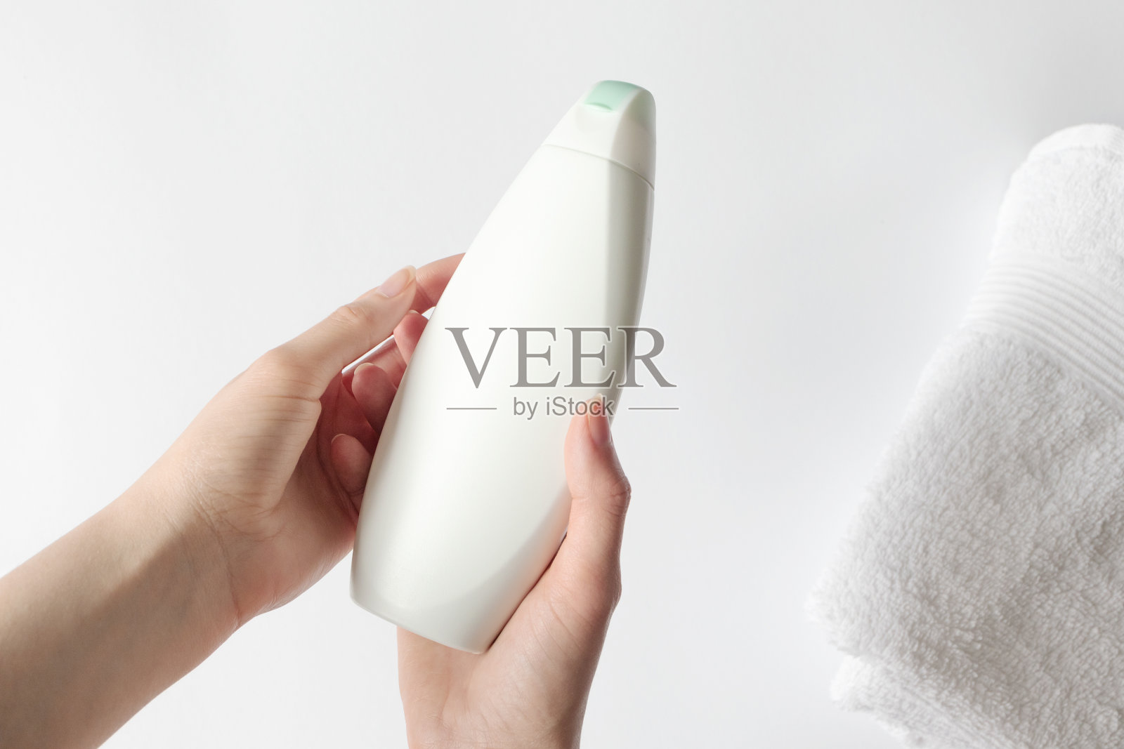 女孩手握沐浴露或洗发水塑料容器模型的白色背景，俯视图。概念美容治疗和卫生照片摄影图片