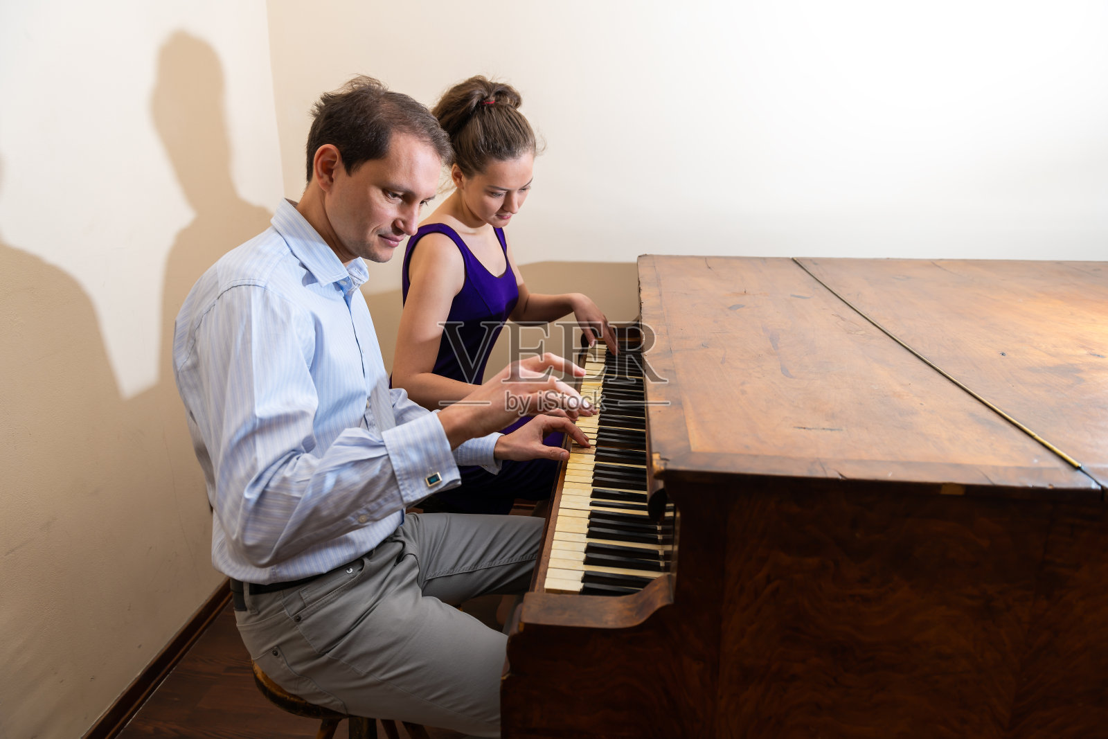 Forte钢琴室与年轻的女子男子浪漫的夫妇坐在钢琴演奏在正式的服装在房间一起音乐会照片摄影图片