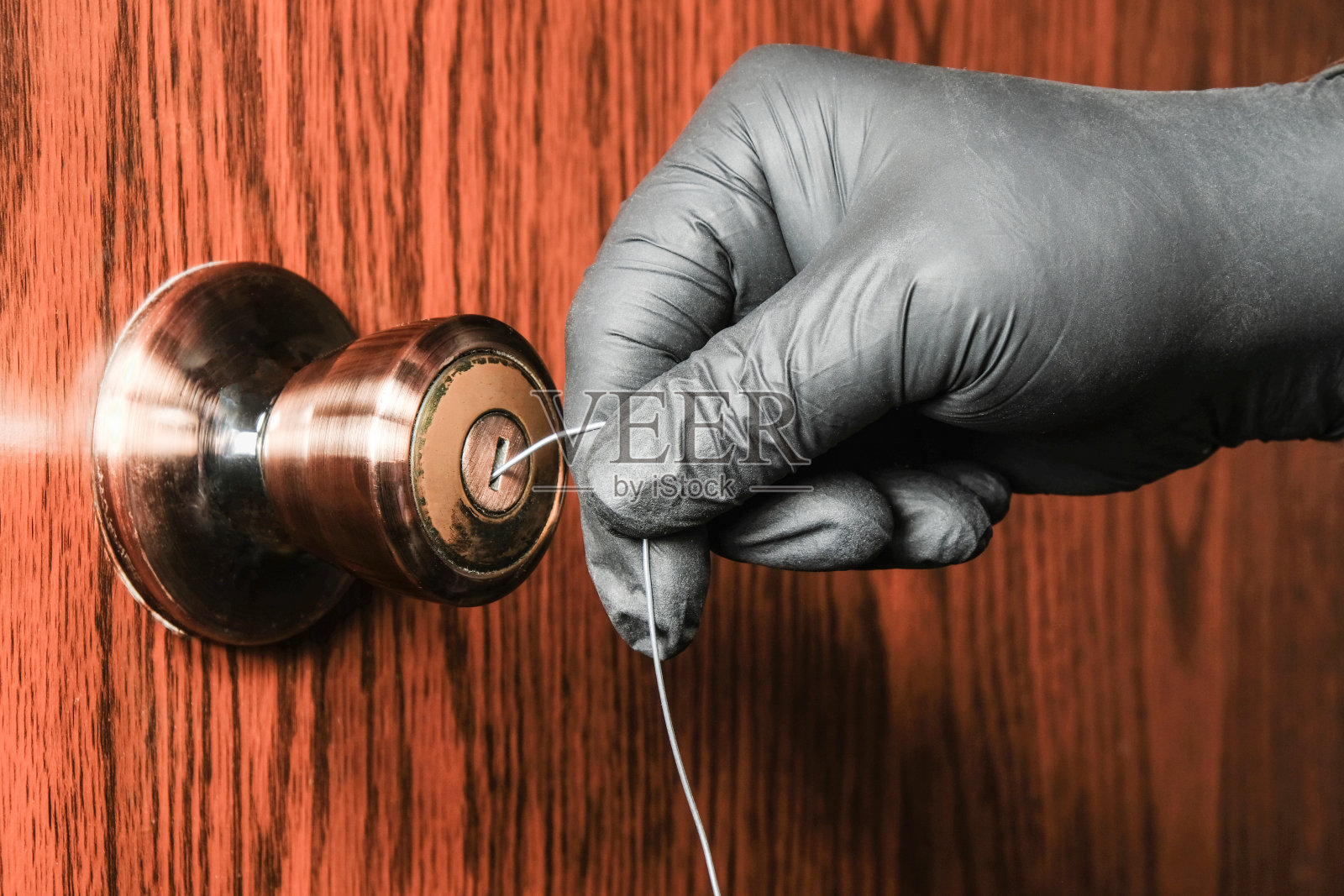 戴着黑手套的小偷用普通钢丝打开一扇装有简单锁的木门。强化家居保护理念照片摄影图片