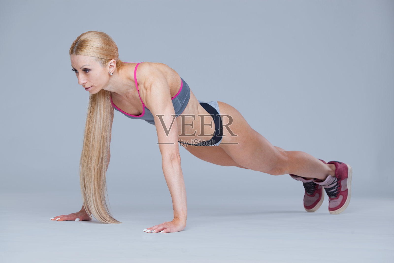 强壮的健身女孩在灰色背景下进行孤立的俯卧撑运动照片摄影图片