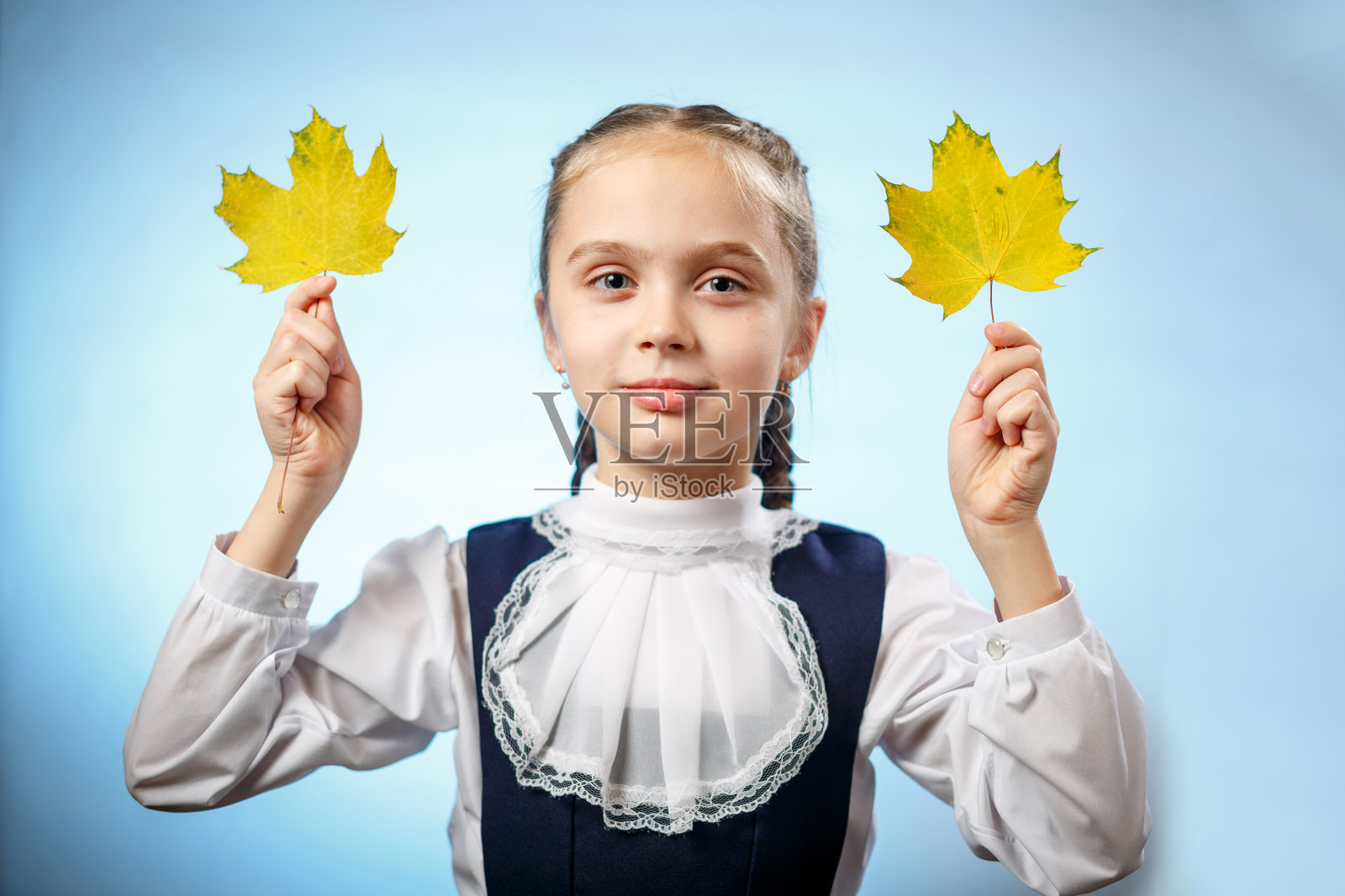 小学女孩与秋天的叶子在蓝色的背景照片摄影图片