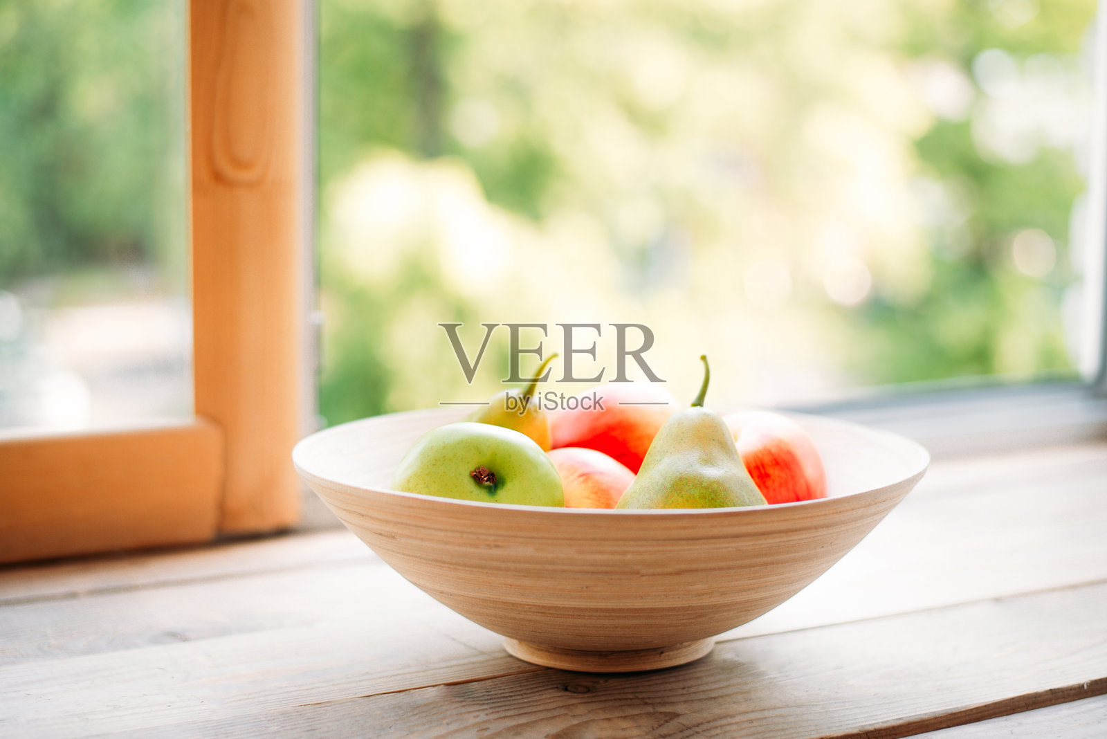 窗台上的一个木盘子里装着苹果和梨。夏日新鲜水果照片摄影图片