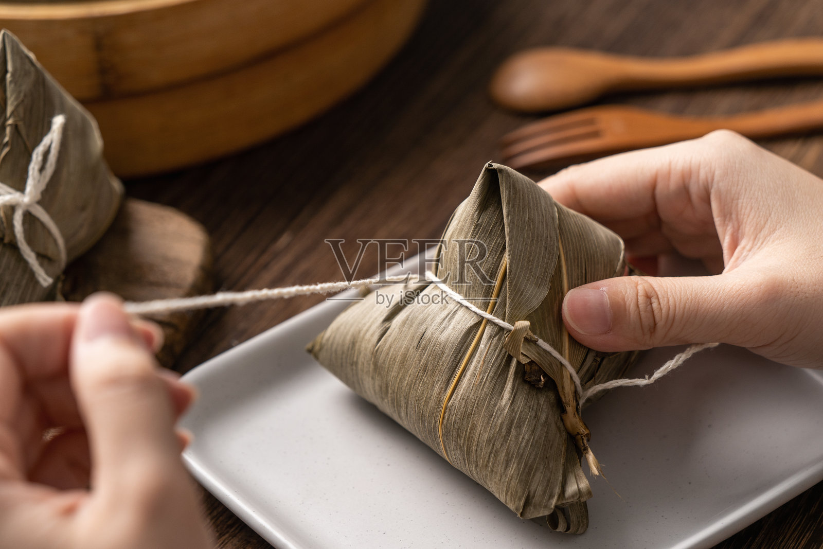 粽子吃——年轻的亚洲妇女在家里的木桌上吃中国传统食物庆祝端午节。照片摄影图片