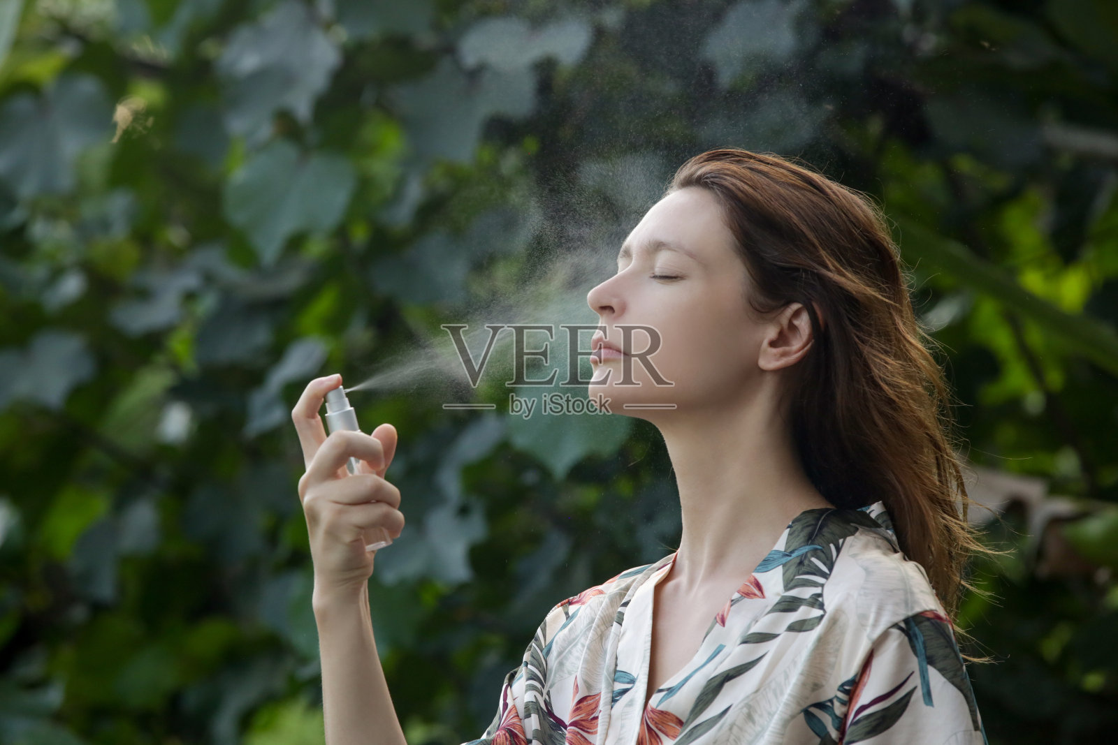 女人在脸上喷洒喷雾，夏日护肤理念照片摄影图片