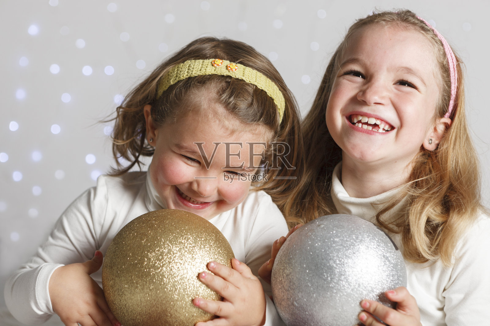 两个可爱有趣的小女孩在圣诞装饰和彩灯的背景照片摄影图片