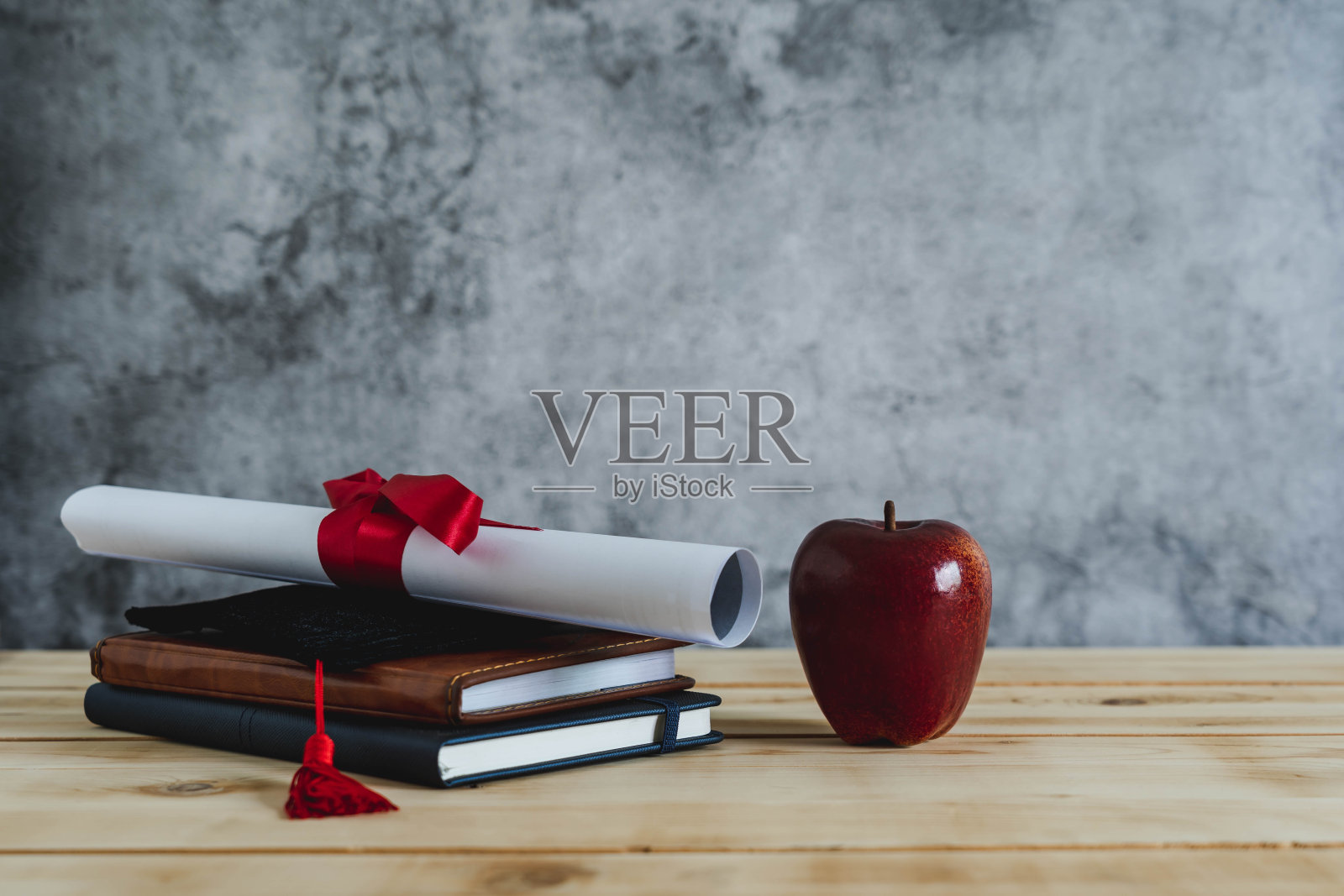 结语教育季背景概念。附件帽证书纸和书和红苹果在现代乡村棕色木制和灰色水泥。大学毕业。照片摄影图片