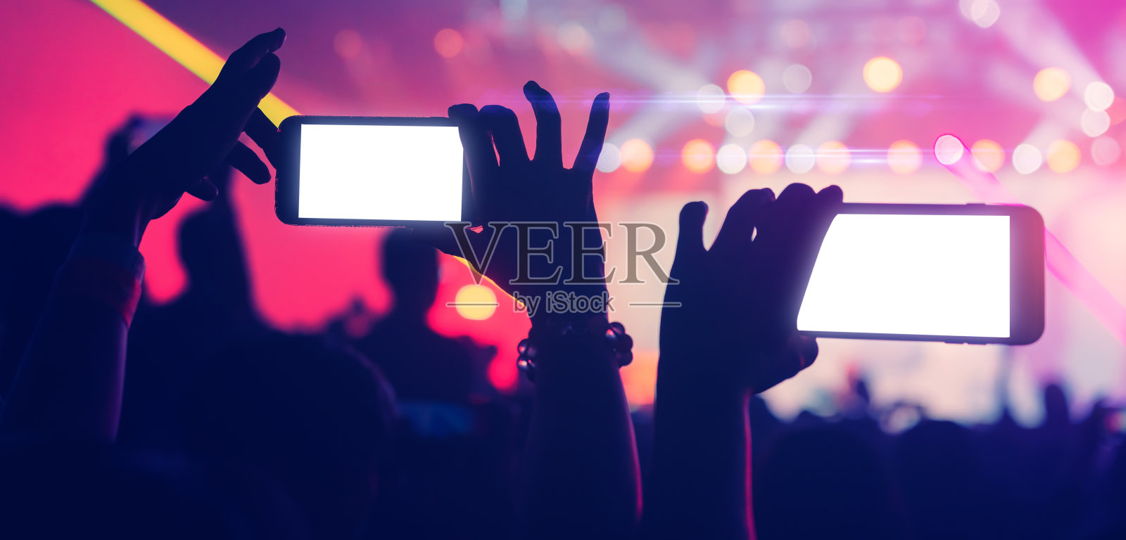 社交媒体概念人群人们手持智能手机捕捉存在的时刻在多彩的灯光音乐会活动与抽象模糊散景背景照片摄影图片