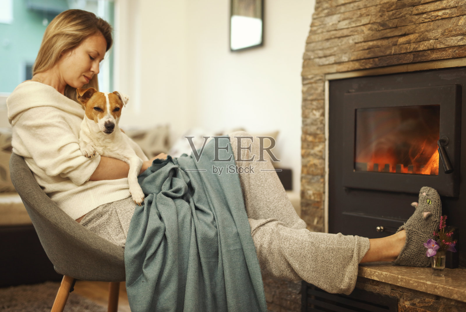舒适的山间周末，女人在舒适的家里穿着放松靠近壁炉，拥抱狗照片摄影图片