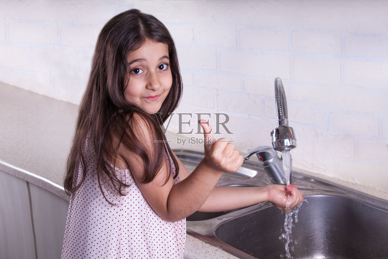 洗手。美丽快乐的女孩洗手，看着镜头，竖起大拇指，微笑着。照片摄影图片