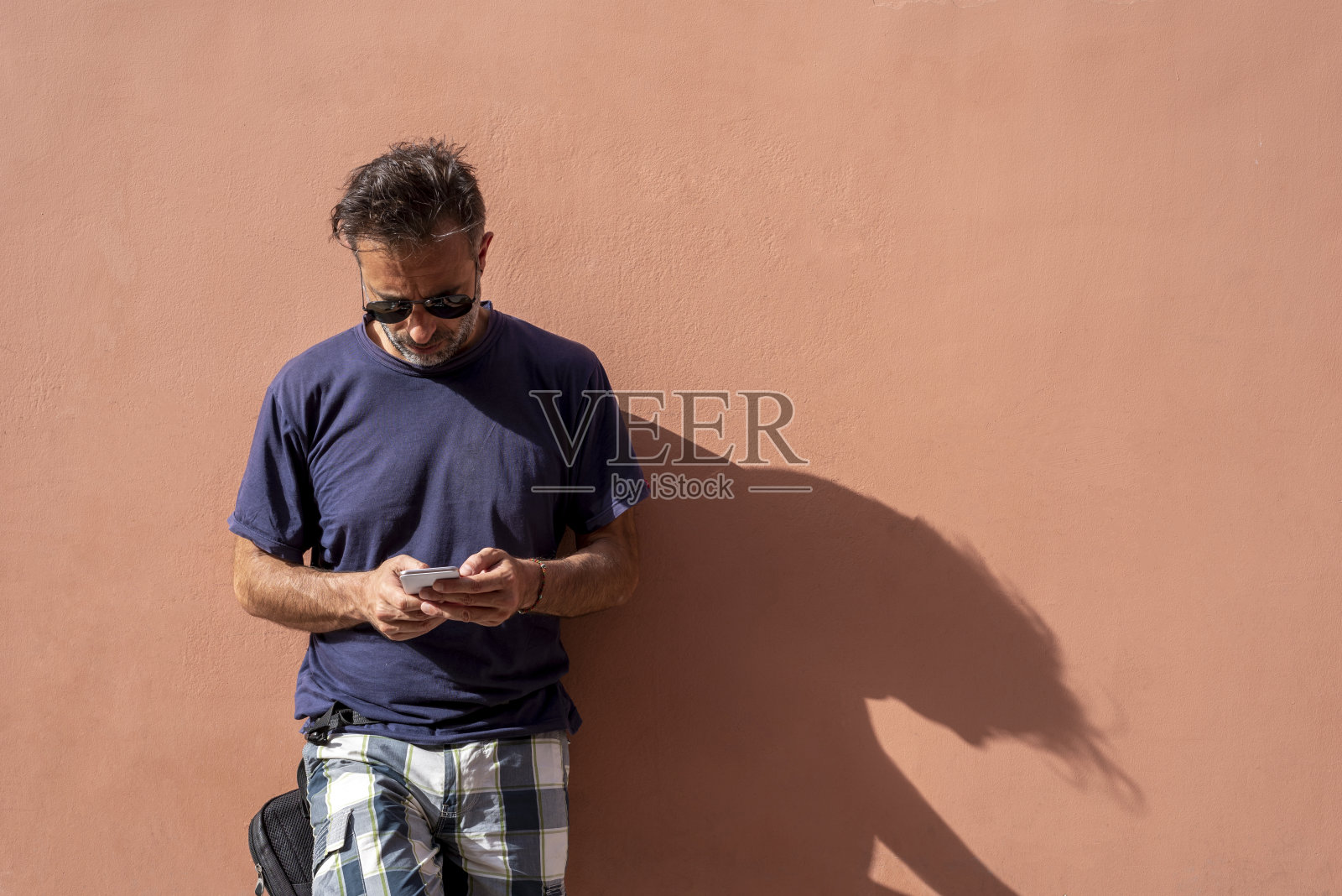 在一个阳光明媚的日子里用手机的帅哥照片摄影图片