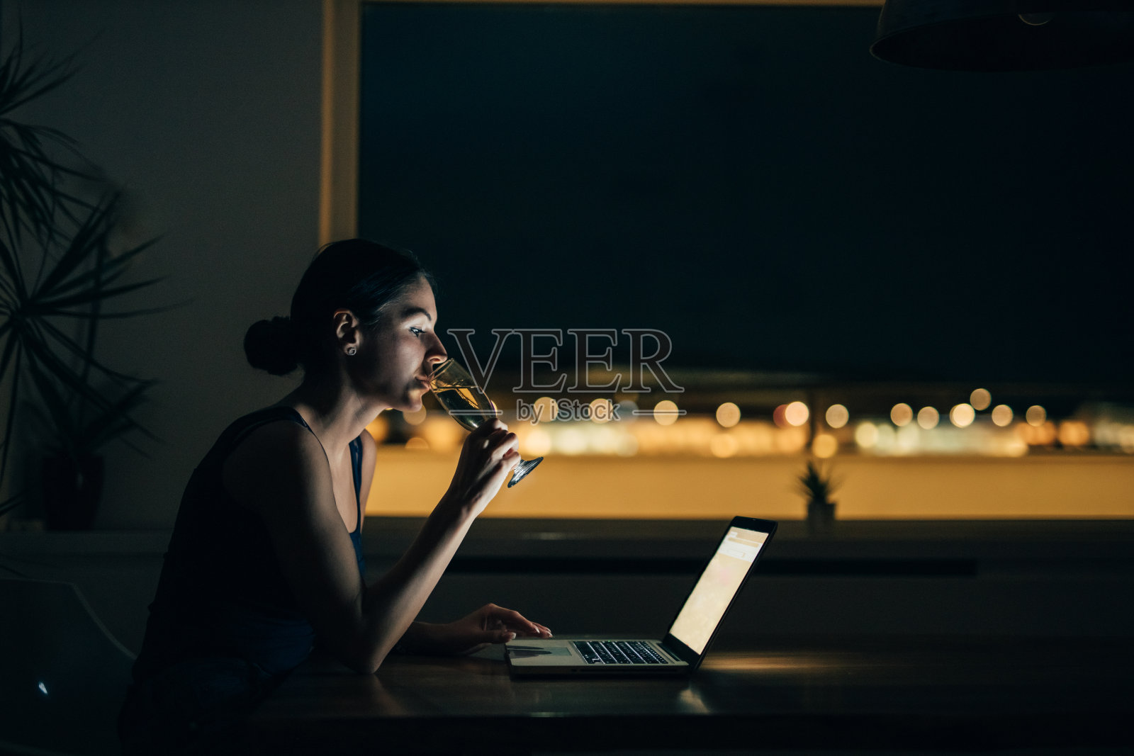 一个女人在阳台上用笔记本电脑喝香槟的肖像。照片摄影图片