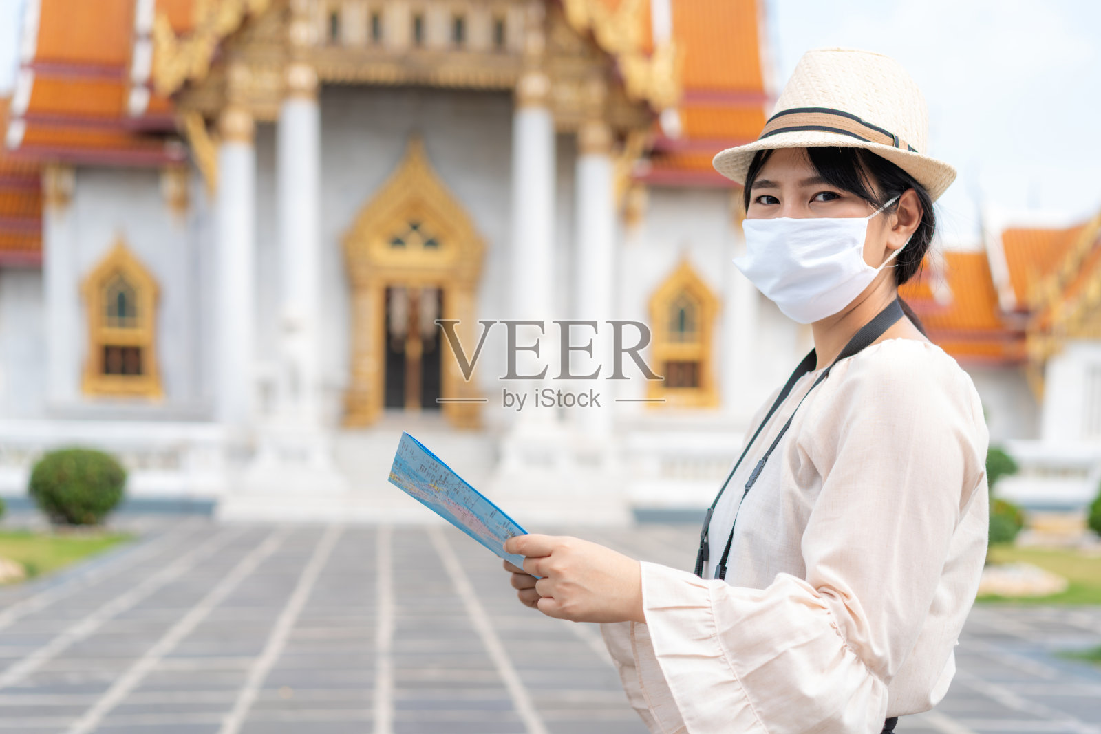在泰国曼谷玉佛寺，一名亚洲女性非常高兴游客戴着口罩旅行，以保护自己免受Covid-19的侵害照片摄影图片