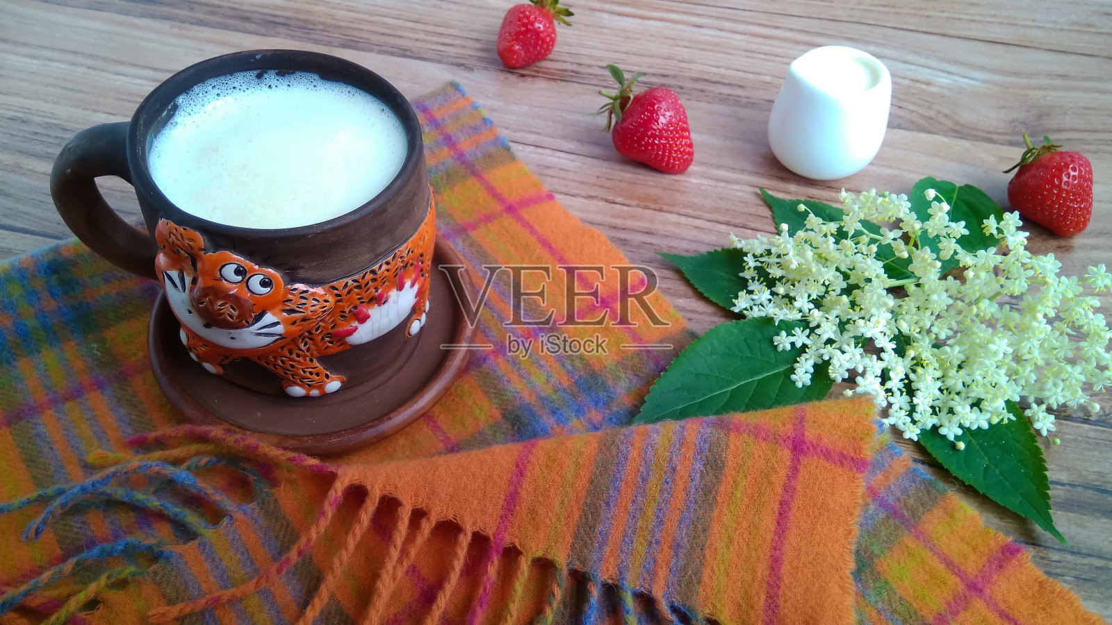 木桌上放着一个陶瓷杯，里面放着自制的新鲜牛奶。照片摄影图片