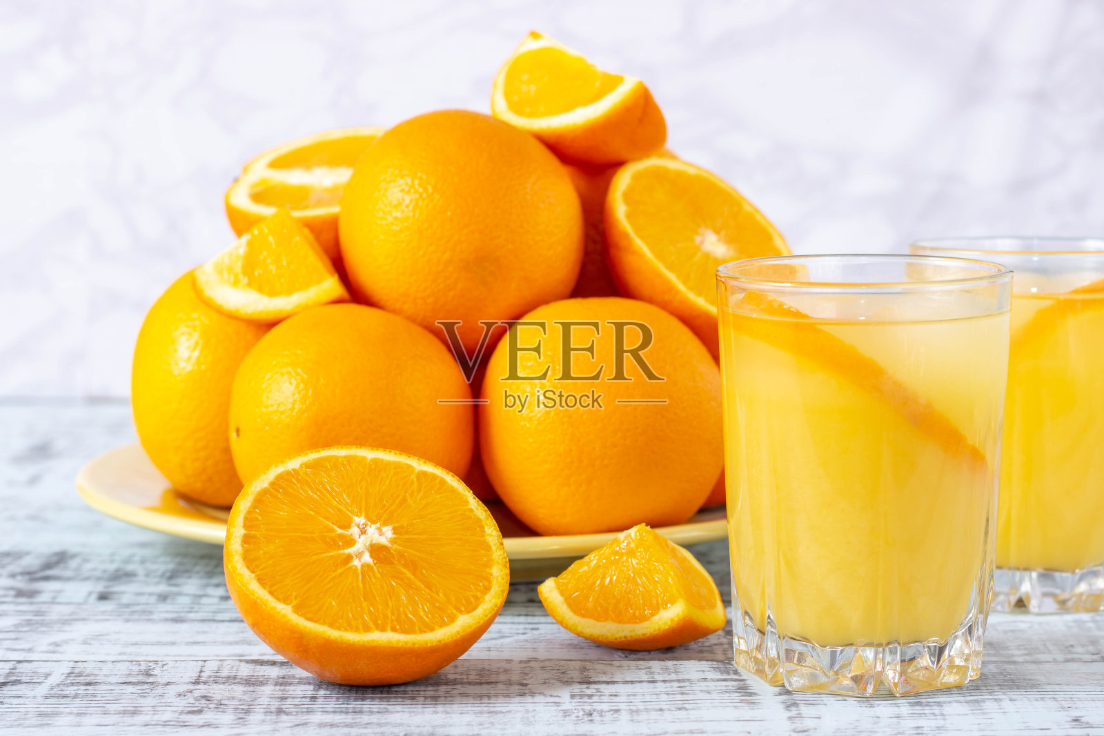 一杯橙汁，木桌上有一个盛着橘子的盘子。鲜榨橙汁。照片摄影图片