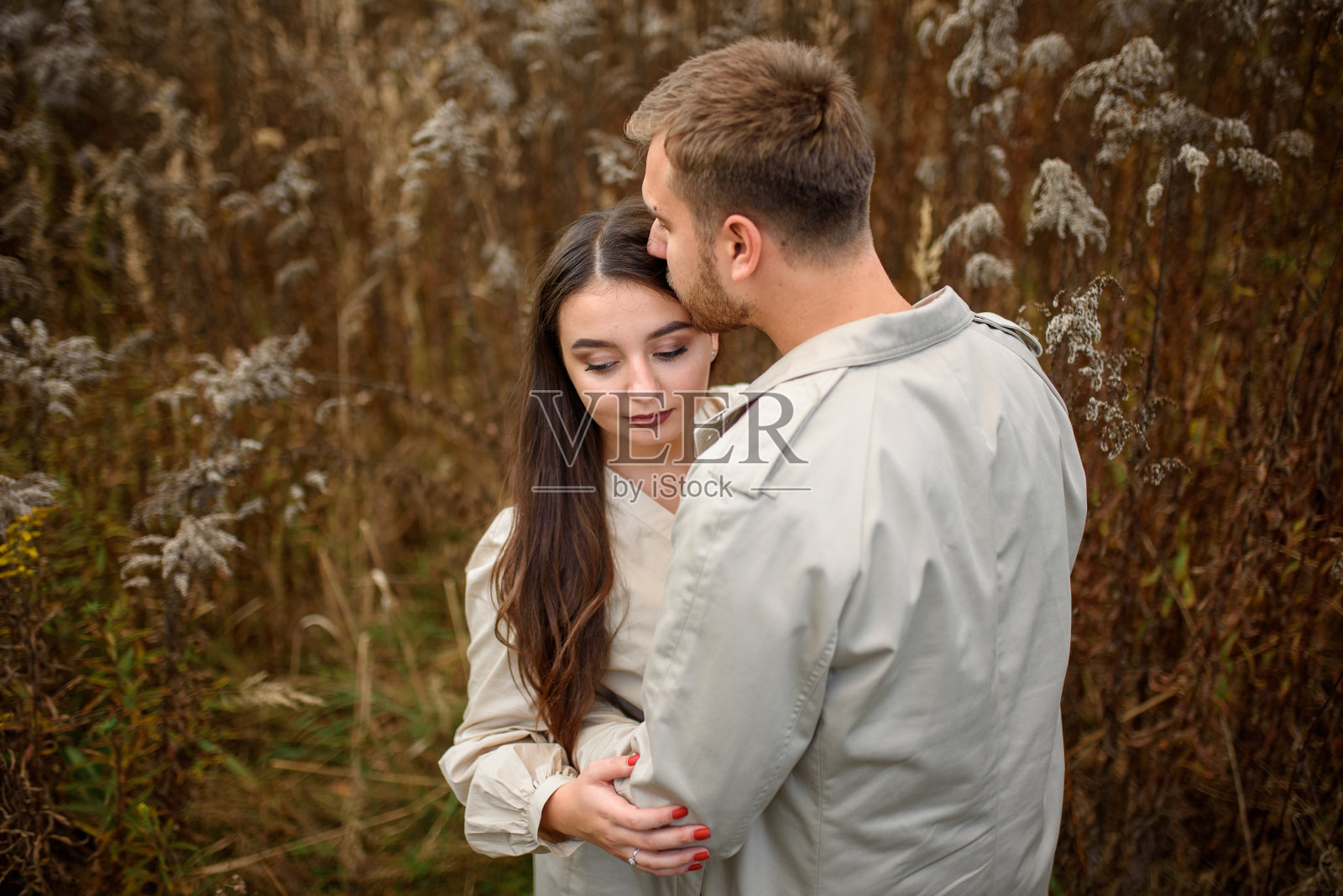 一个美丽的年轻幸福的夫妇在秋天的公园里拥抱在一起的亲密镜头照片摄影图片