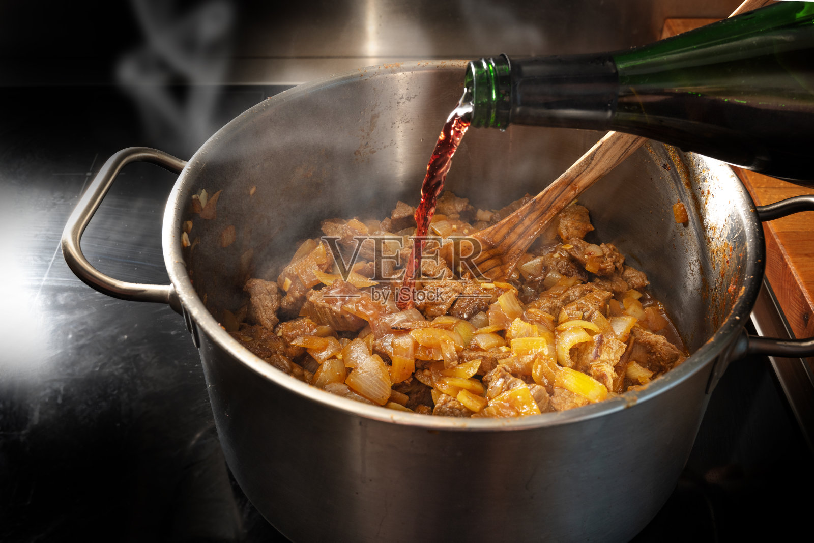 红酒从瓶子里倒进锅里，与炖牛肉一起去釉，在家做饭的概念，选择重点照片摄影图片