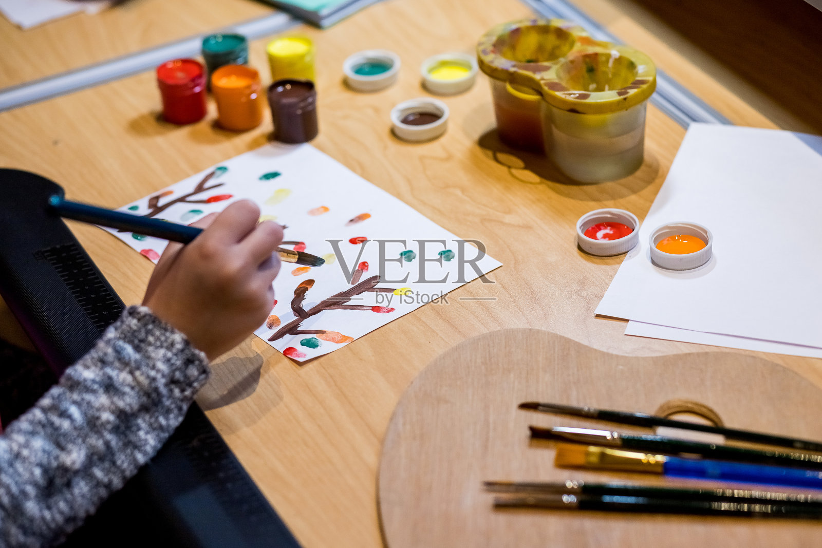 孩子的手画在桌子上与水粉，艺术用品，选择性的焦点。学习绘画概念，用水彩笔和水彩盒在木桌上飞溅，为孩子创造艺术工作场所。照片摄影图片