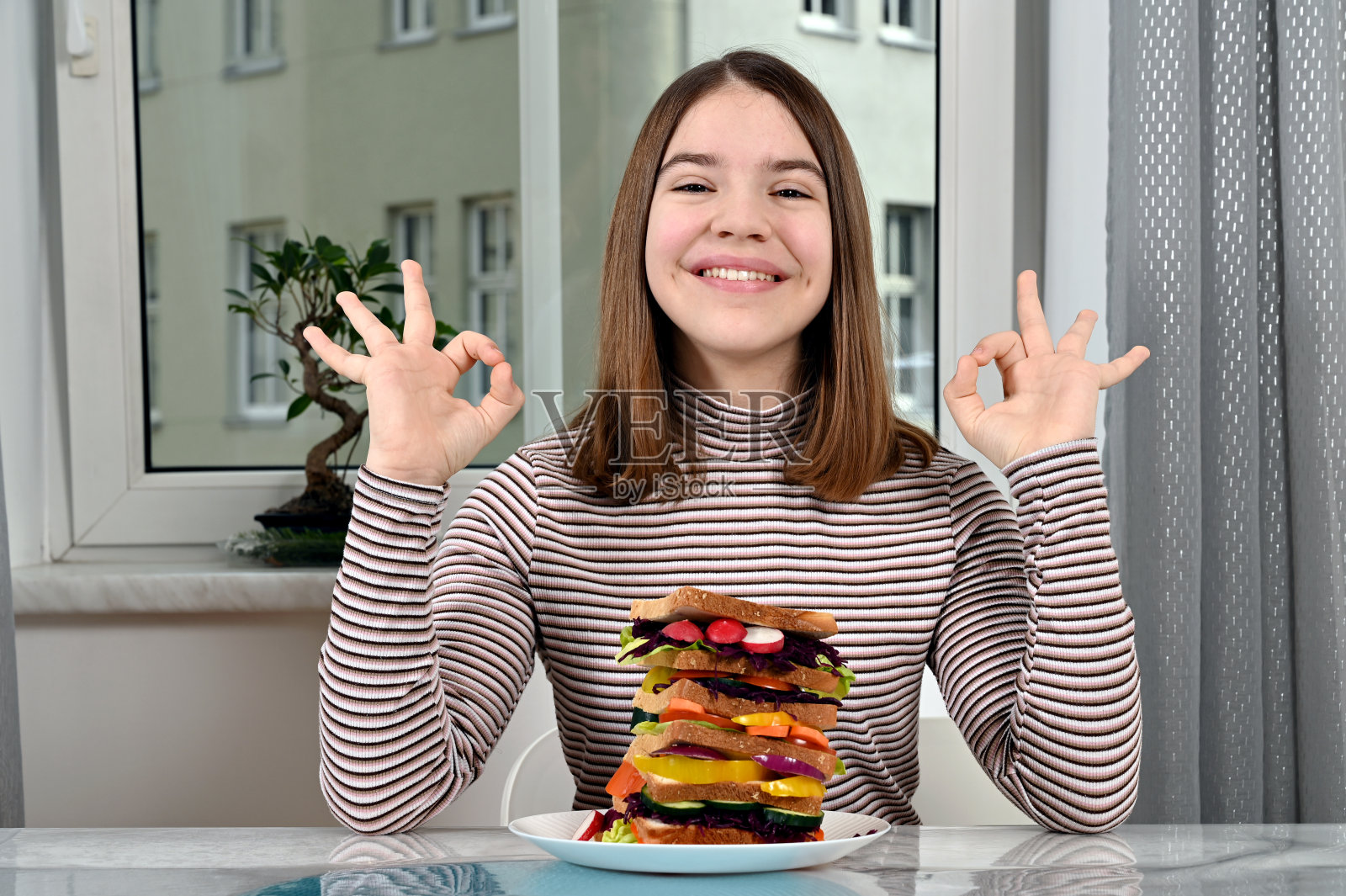 有素食三明治和ok手势的快乐少女照片摄影图片