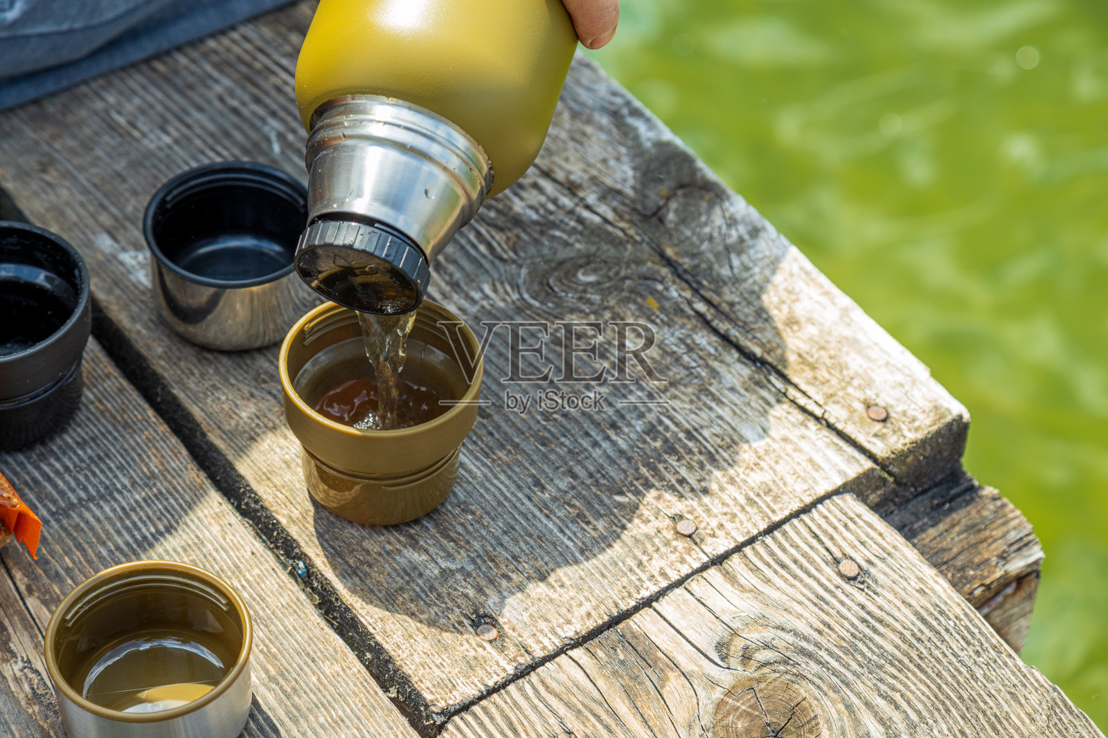 热水瓶户外木制风化表面与复印空间。把茶倒进杯子里。照片摄影图片
