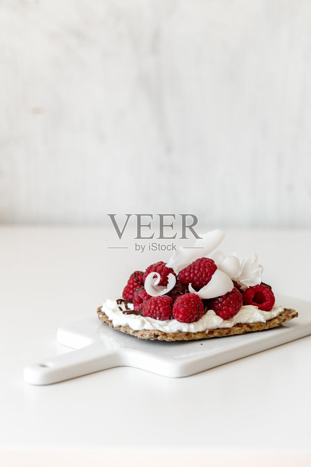零食脆饼，奶油奶酪和新鲜的树莓在白色大理石背景。健康食品的概念。照片摄影图片