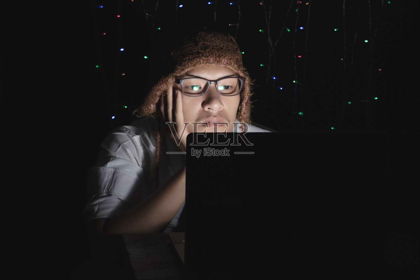 年轻帅气的男子在笔记本电脑上用光线从屏幕反射到面部的技术。照片摄影图片
