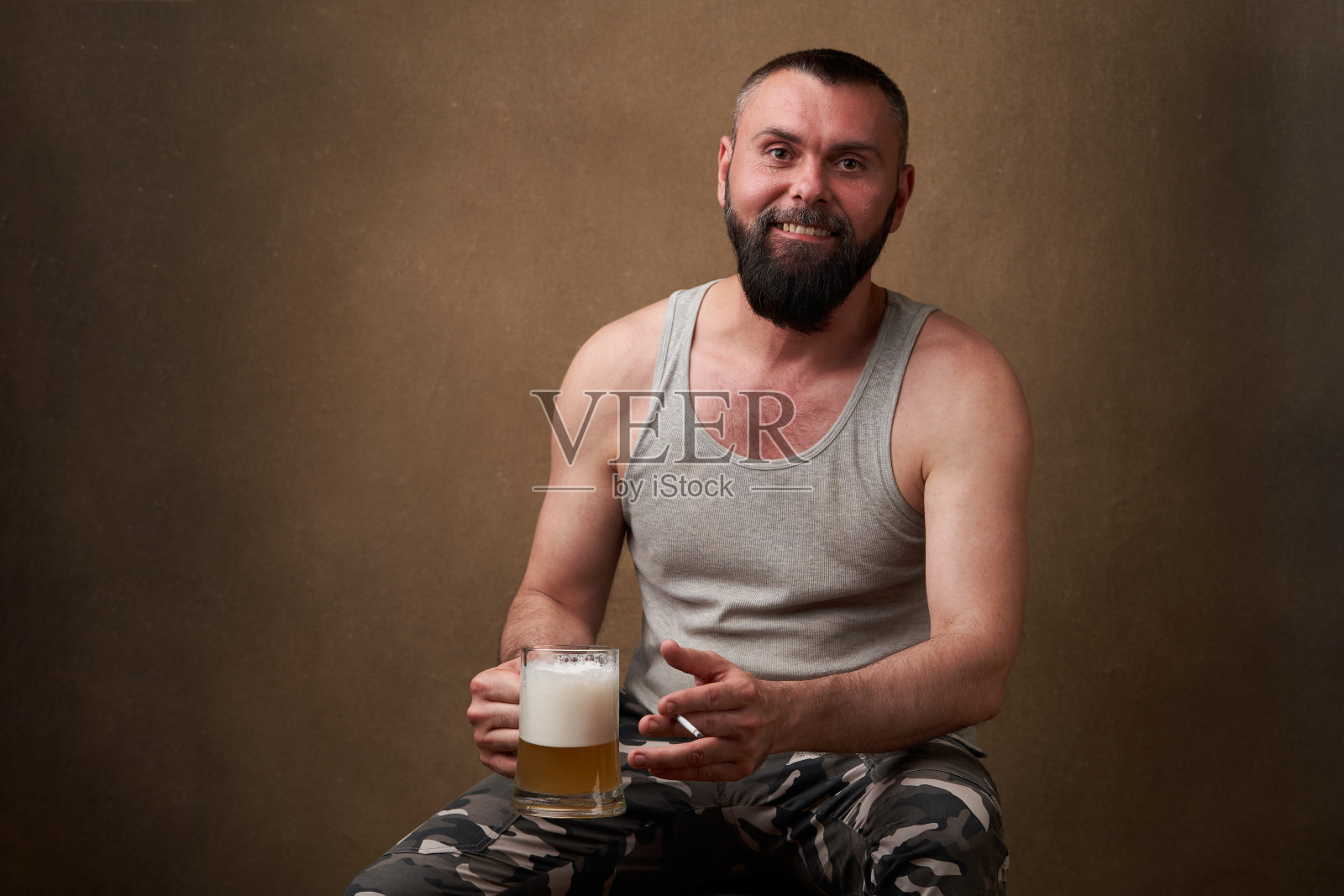 一个留着胡子的英俊男子的肖像，手里拿着一大杯啤酒照片摄影图片