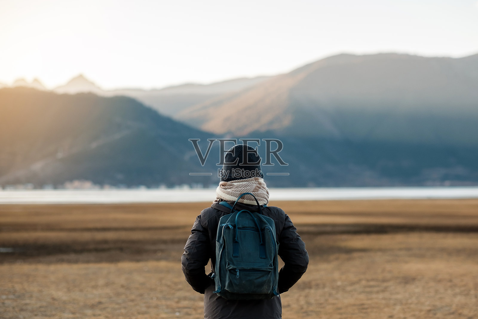 潮女旅行者与毛衣和背包在纳帕湖旅行，快乐的年轻徒步者看山和日落在旅行香格里拉，云南，中国。探索，冒险和亚洲独自旅行的概念照片摄影图片
