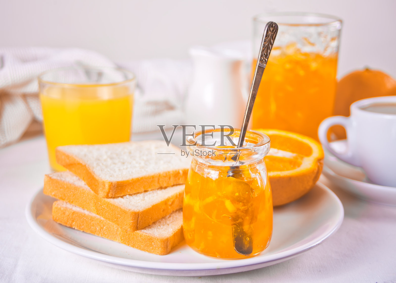 面包吐司配橙酱，白色背景上有几杯橙汁。早餐的概念。照片摄影图片
