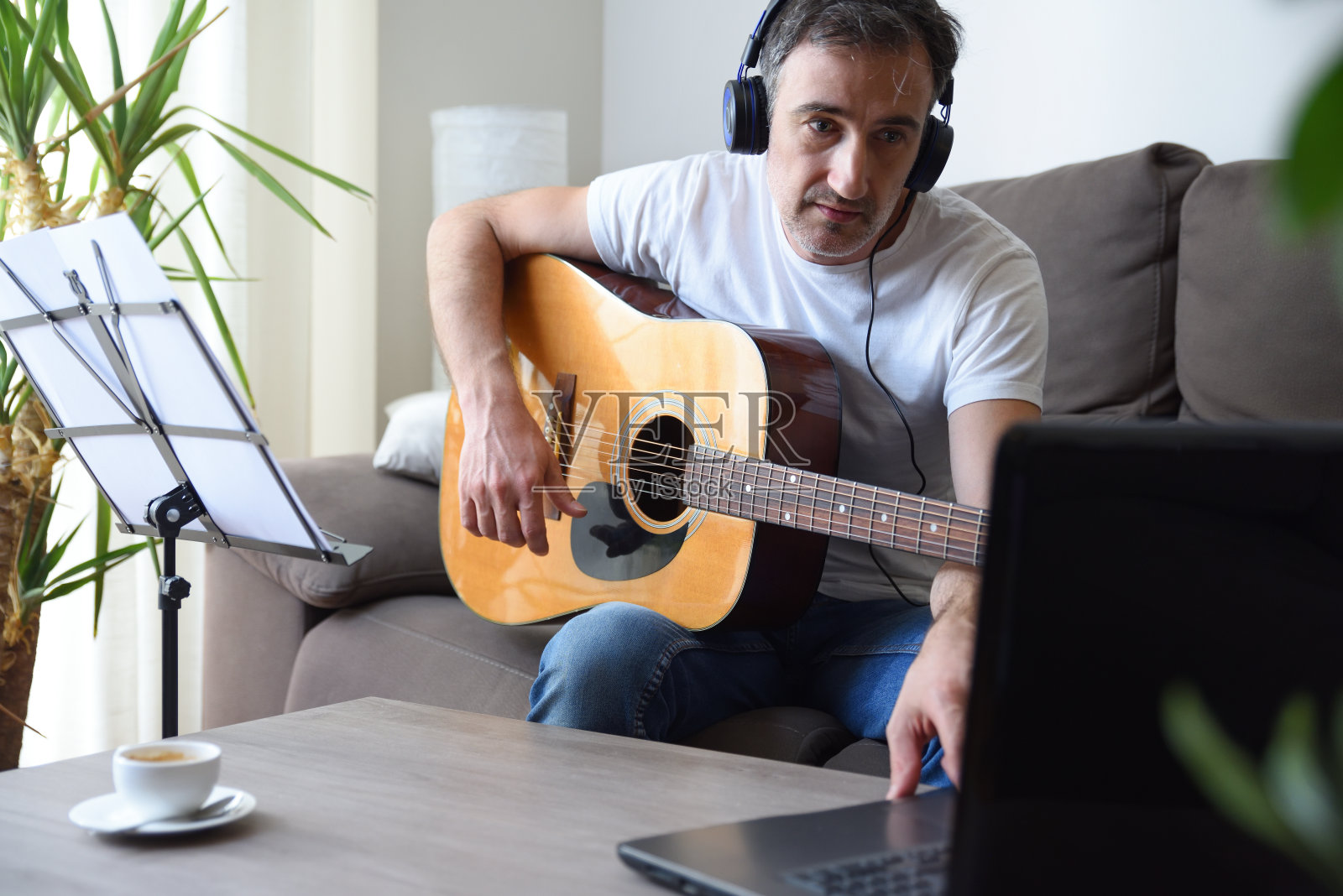 男人在家用吉他听和弹歌曲照片摄影图片