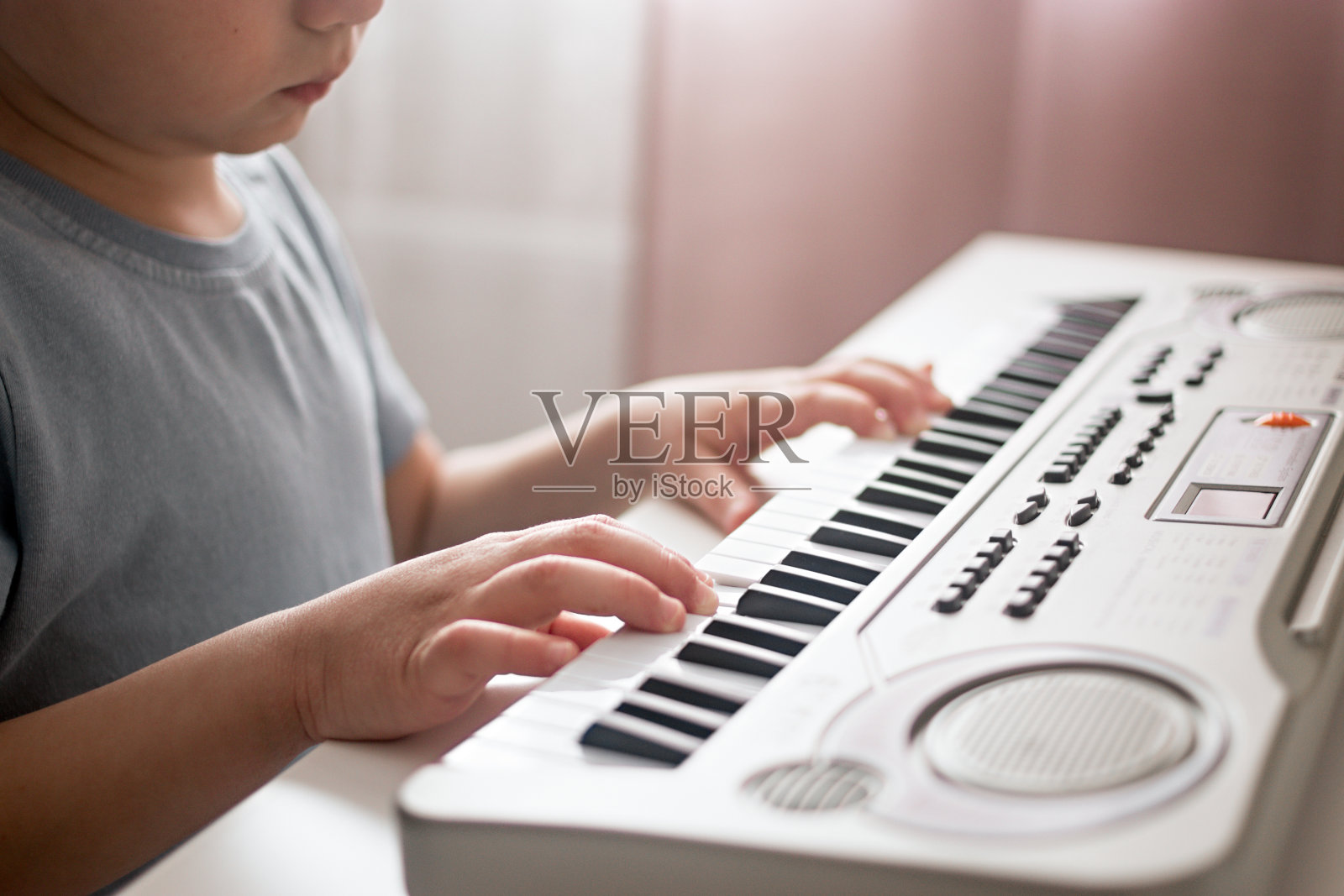近距离的孩子在弹奏钢琴键盘。男孩学习玩合成器照片摄影图片
