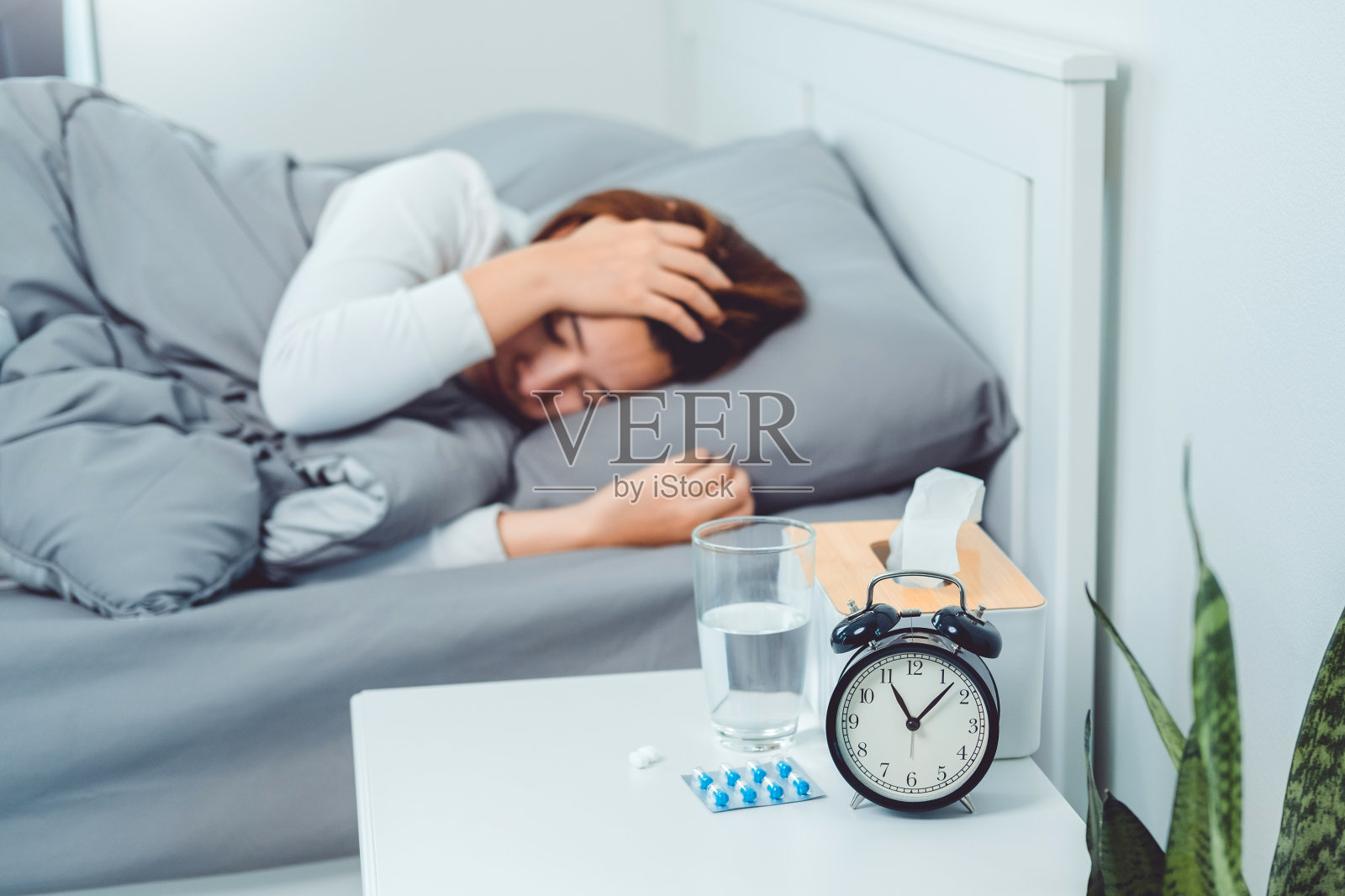 亚洲妇女流感和感冒，生病和睡在家里的床上。发热、咳嗽、擤鼻涕、用纸巾打喷嚏。感觉不适问题的治疗理念照片摄影图片